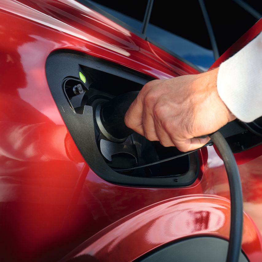 Nejaká osoba zapája nabíjací kábel do vozidla VW.