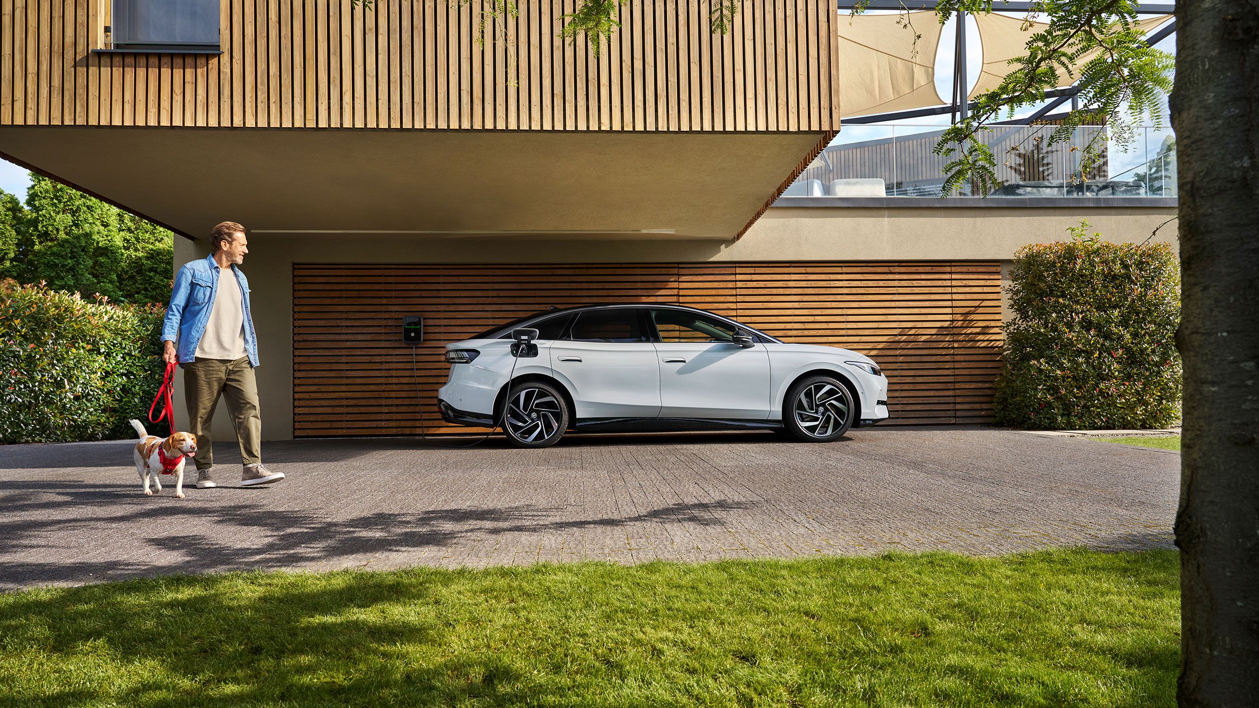 Muž so psom vedľa VW ID. Nabíjacia nástenná nabíjačka.