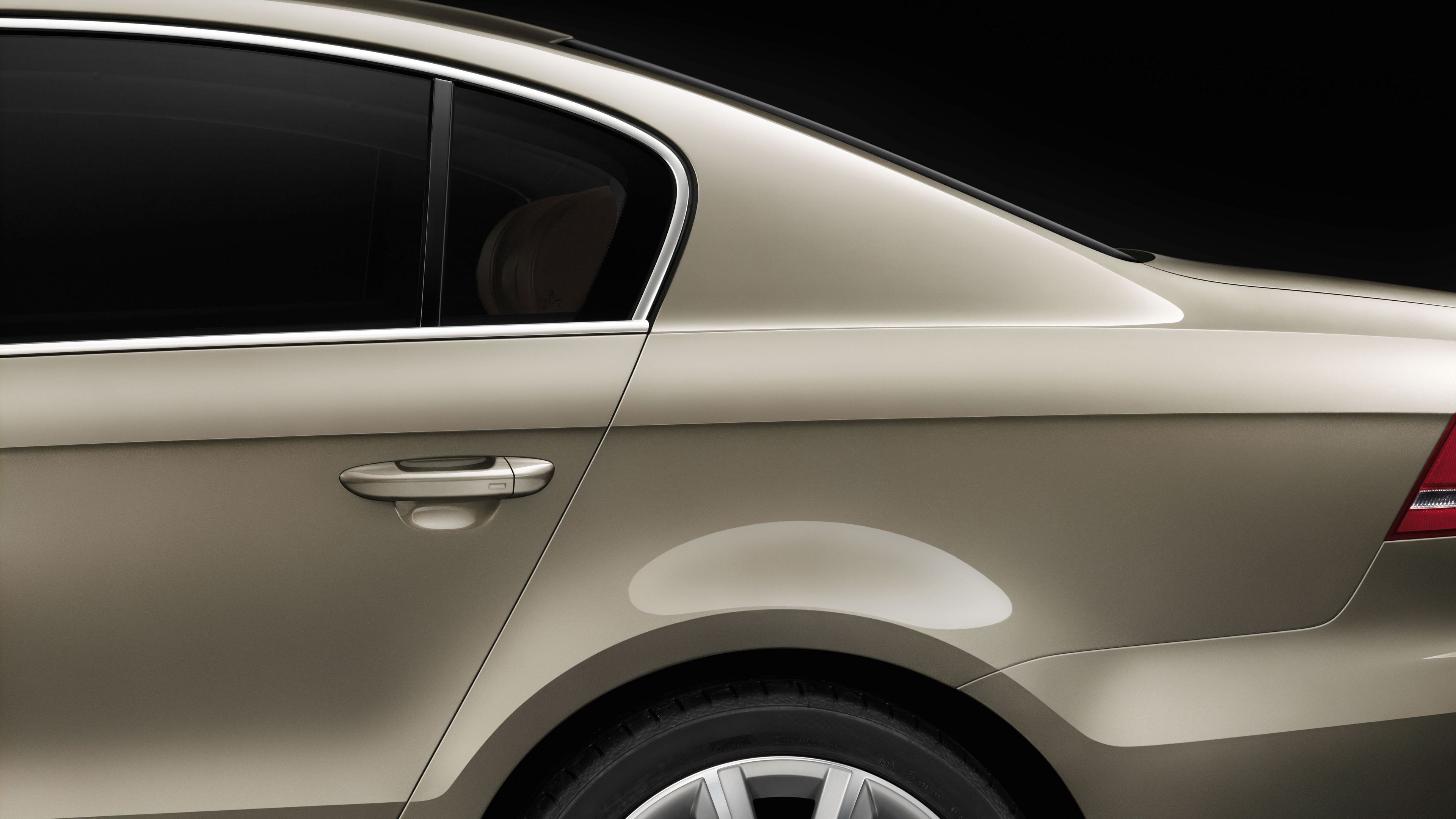 Bočná časť osobného automobilu so zatvorenými dverami a tónovaným oknom. Automobil má elegantnú hnedú metalízovú farbu. Pozadie je čierne a zvýrazňujúce detaily vozidla.