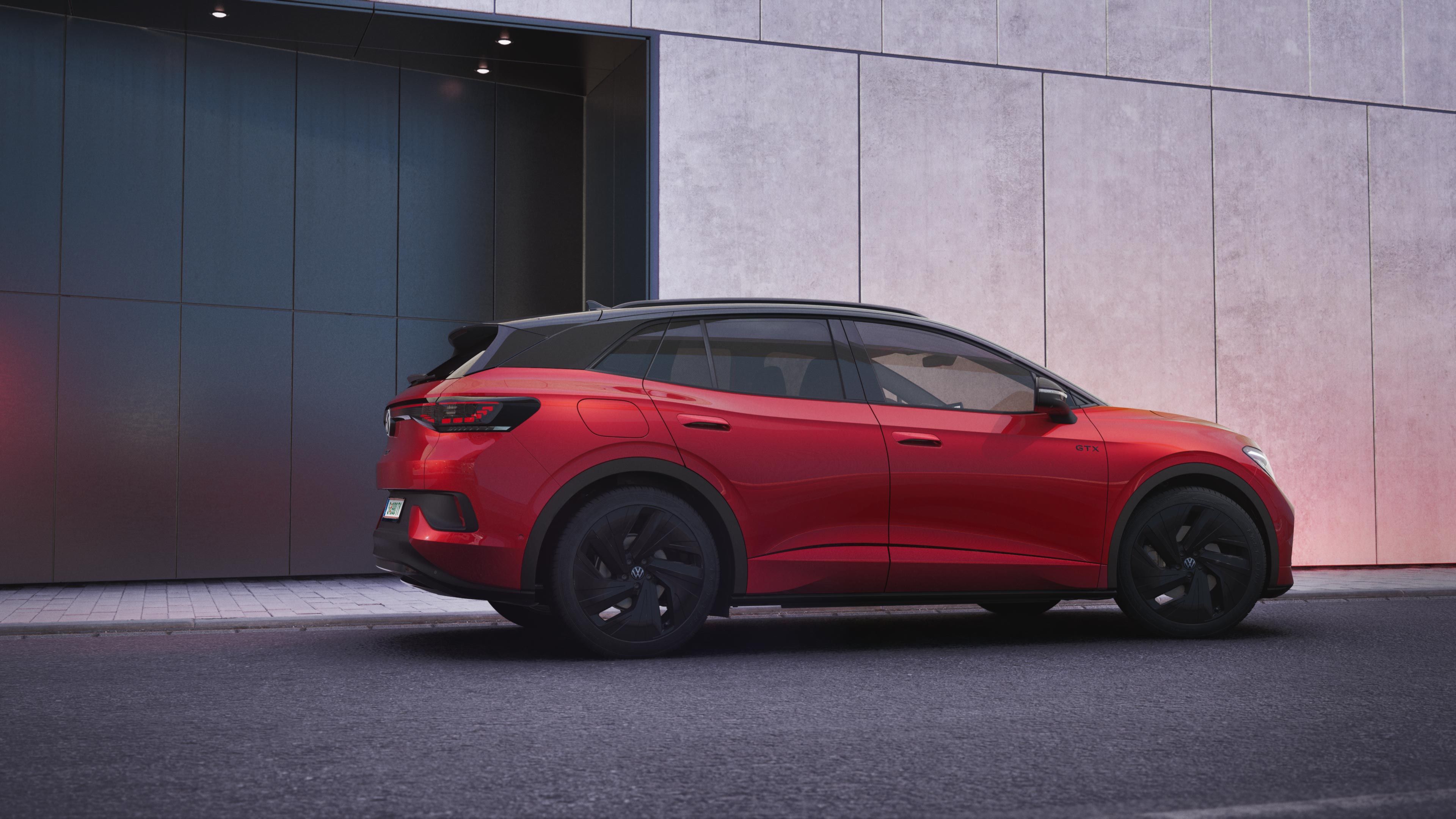 Červený VW ID.4 GTX stojí pri chodníku vedľa modernej budovy so sivou a antracitovou fasádou..
