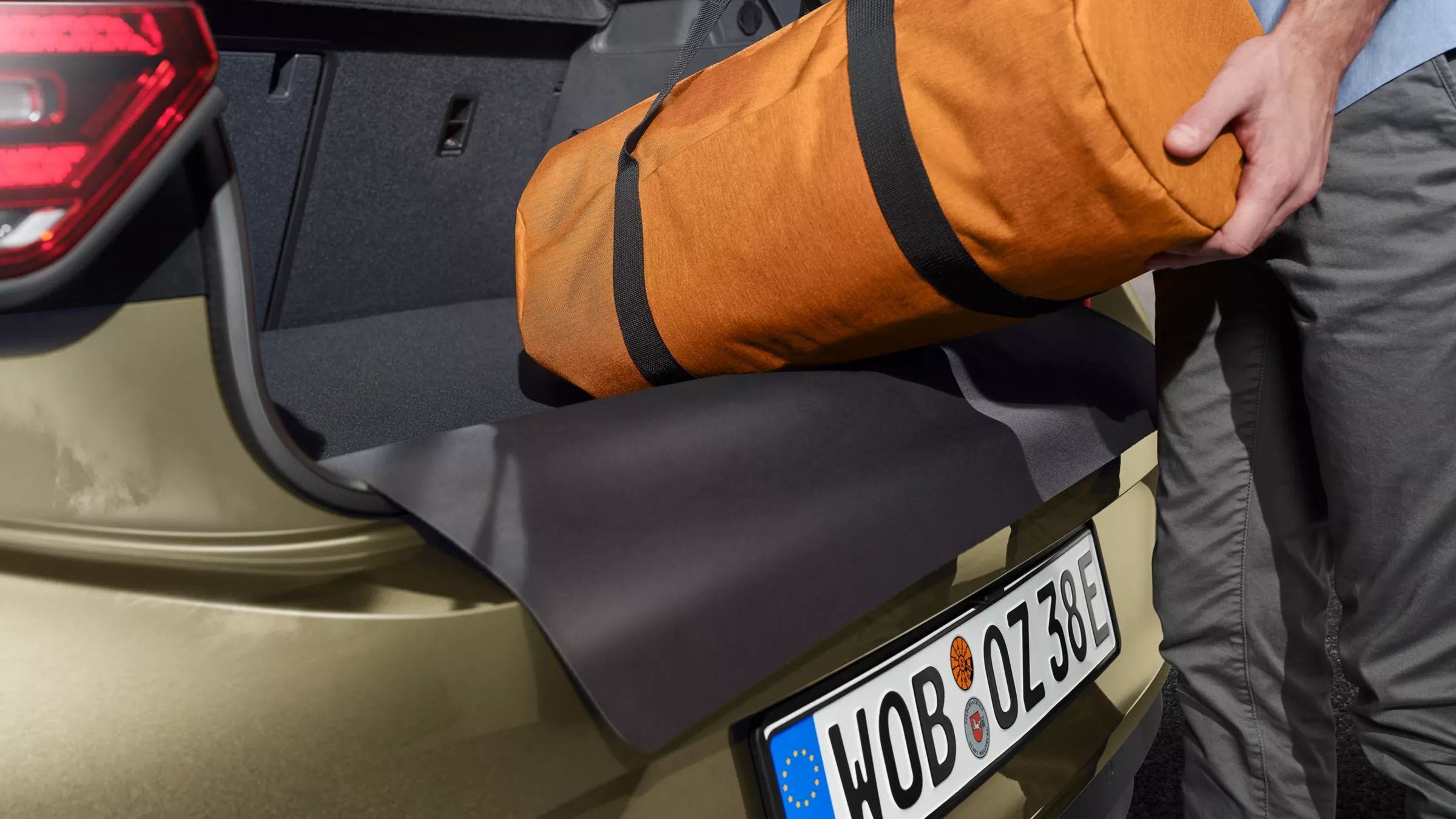 Niekto položí tašku na obojstrannú rohož do batožinového priestoru vozidla VW Accessories v batožinovom priestore vozidla VW ID.3.