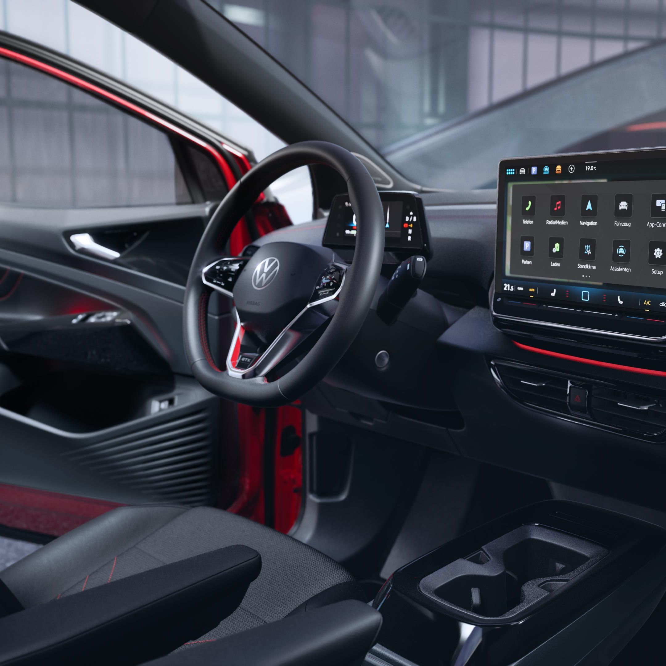 VW ID.4 GTX interiér s výhľadom na predné sedadlá, multifunkčný volant, digitálny prístrojový displej, palubná doska s displejom systému infotainment a ambientné osvetlenie. Dvere vodiča sú otvorené a ponúkajú výhľad na budovu, pri ktorej vozidlo stojí.