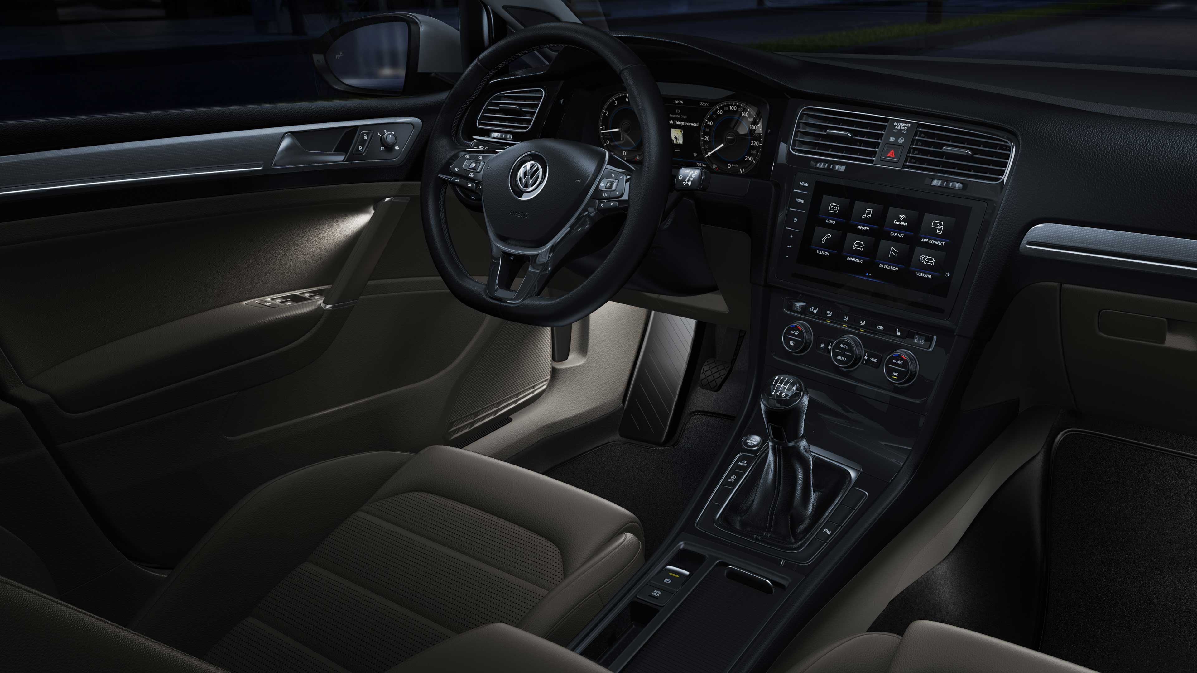 Interiér automobilu s osvetlením priestoru pre nohy a lakťovej opierky vo dverách. Vidieť tiež prístrojový panel, volant a sedadlá. Na prístrojovej doske sa nachádzajú rôzne ovládacie prvky a displeje. Automobil má manuálnu prevodovku.