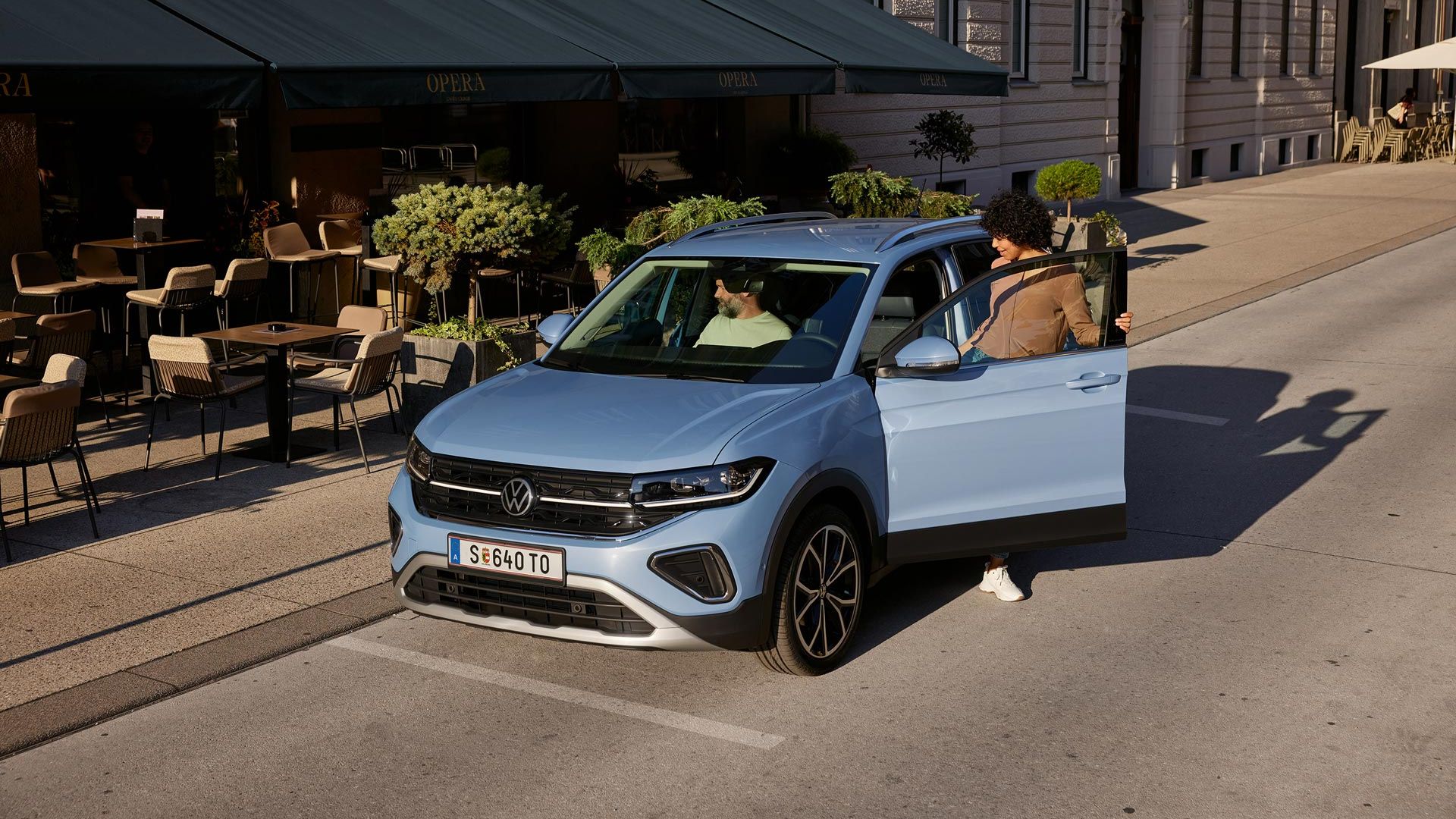 Do modrého VW T-Cross, ktorý je zaparkovaný pred kaviarňou, nastúpi žena na strane vodiča.
