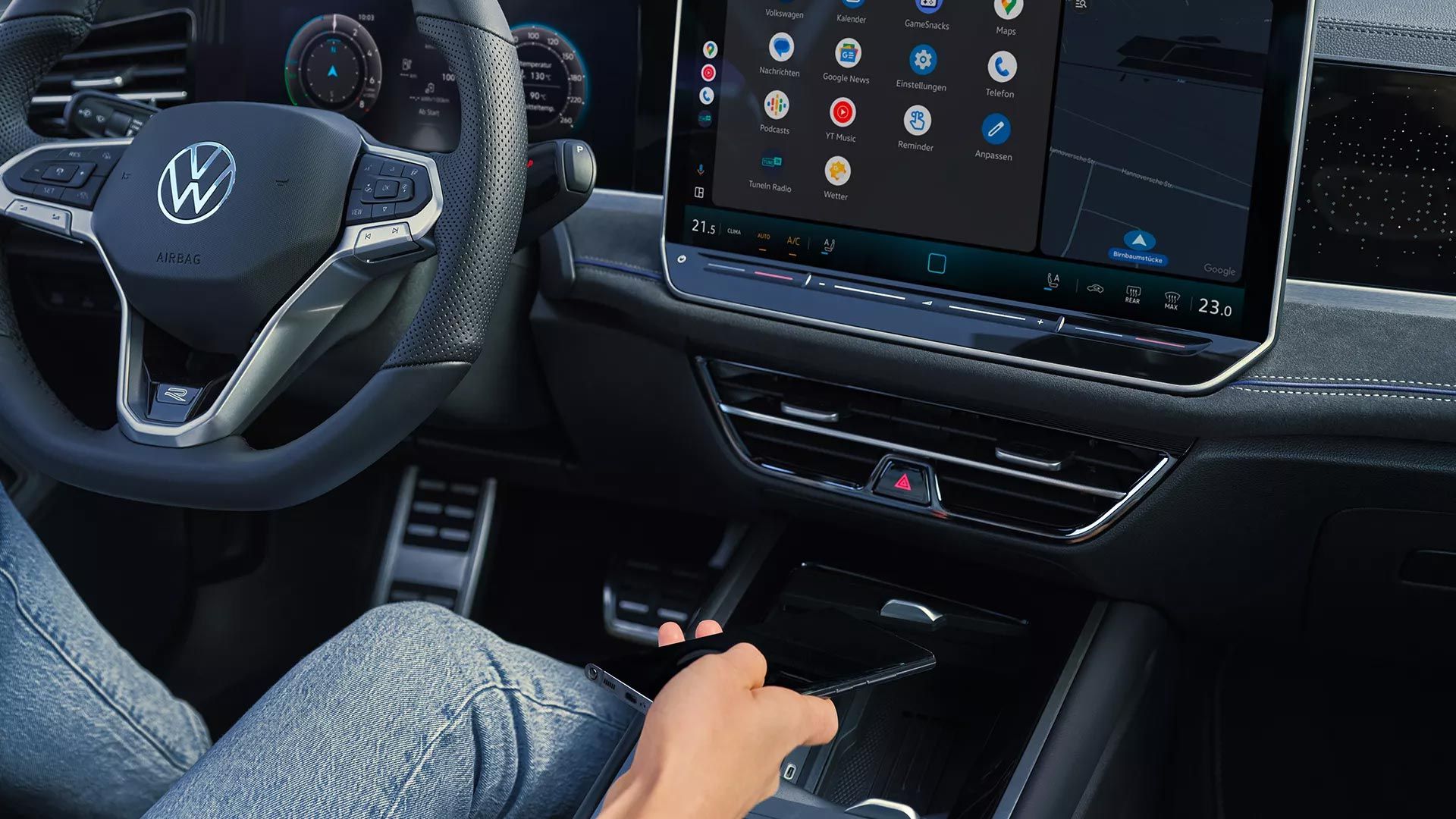 Interiér s pohľadom na priehradku pre indukčné nabíjanie vo VW Passat. Čiastočne vidieť volant , digitálny prístrojový panel a veľký displej systému infotainment integrovaný do palubnej dosky.