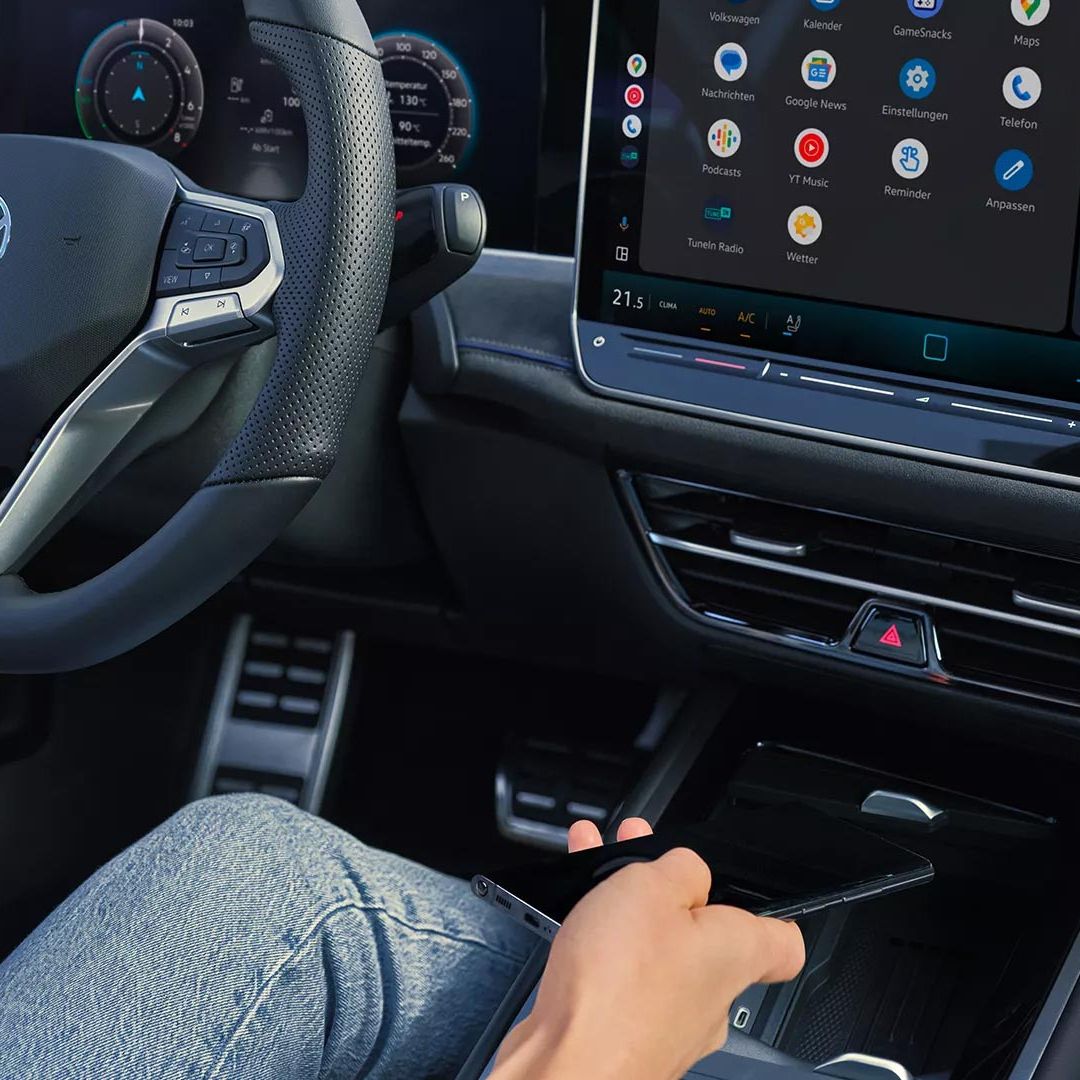 Interiér s pohľadom na priehradku pre indukčné nabíjanie vo VW Passat. Čiastočne vidieť volant , digitálny prístrojový panel a veľký displej systému infotainment integrovaný do palubnej dosky.