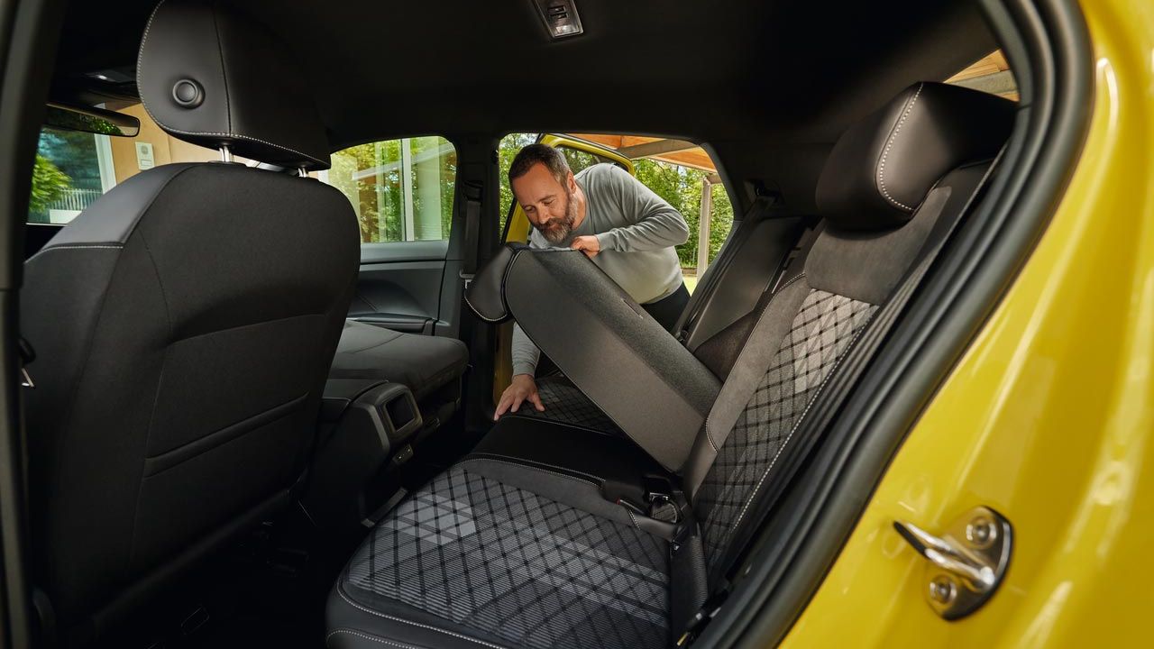 Muž sklopí zadné sedadlo žltého VW T-Cross dopredu.