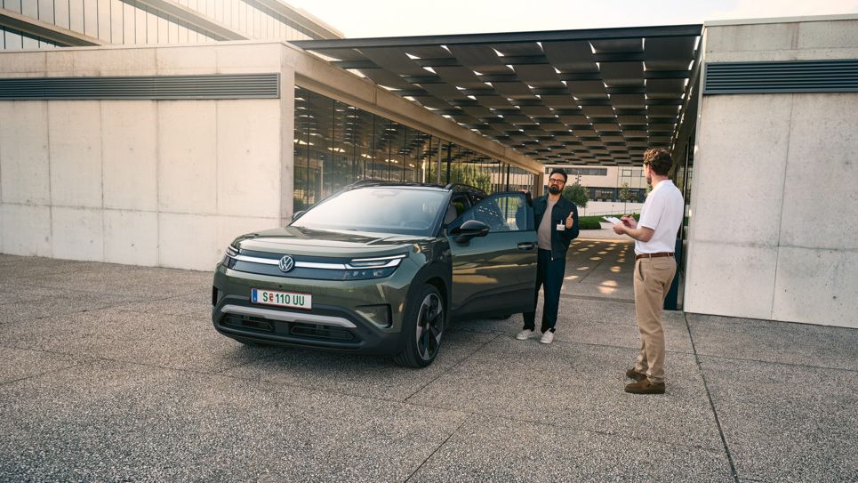 Muž nastúpi do VW ID. Cross a rozpráva sa s inžinierom s klipbordom v ruke.