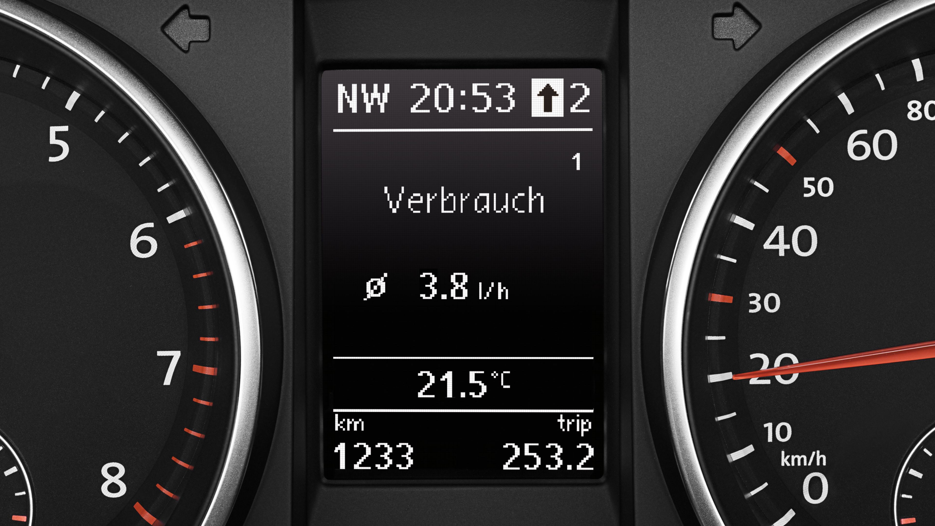 Digitálny displej na palubnej doske vozidla zobrazuje smer, čas, spotrebu 3.8 l/h, teplotu 21.5°C a prejdenú vzdialenosť 1 233 km. Okolo displeja sú viditeľné ukazovatele rýchlosti a otáčok.