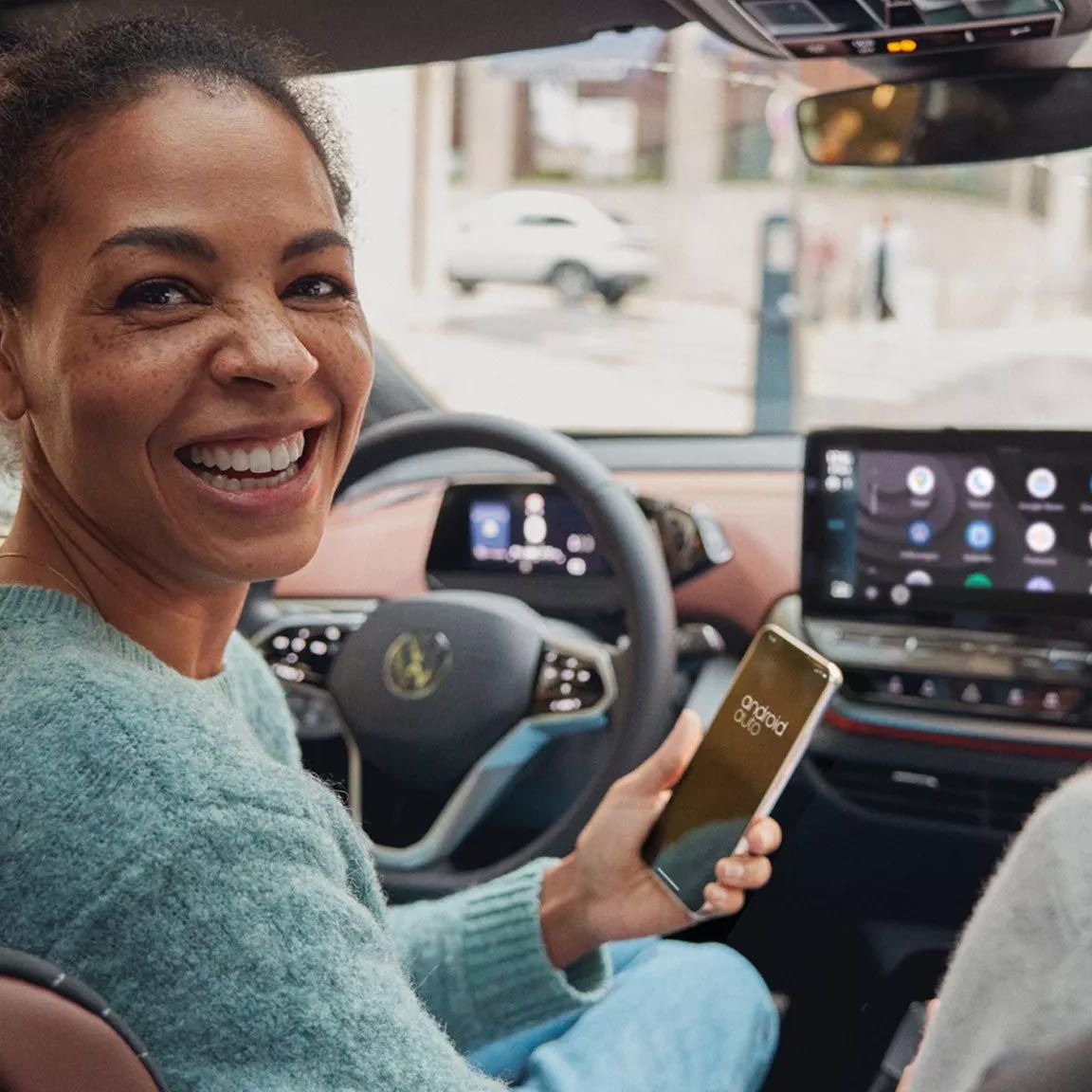 Usmievajúca sa žena so smartfónom v ruke používa Android Auto v modeli ID.