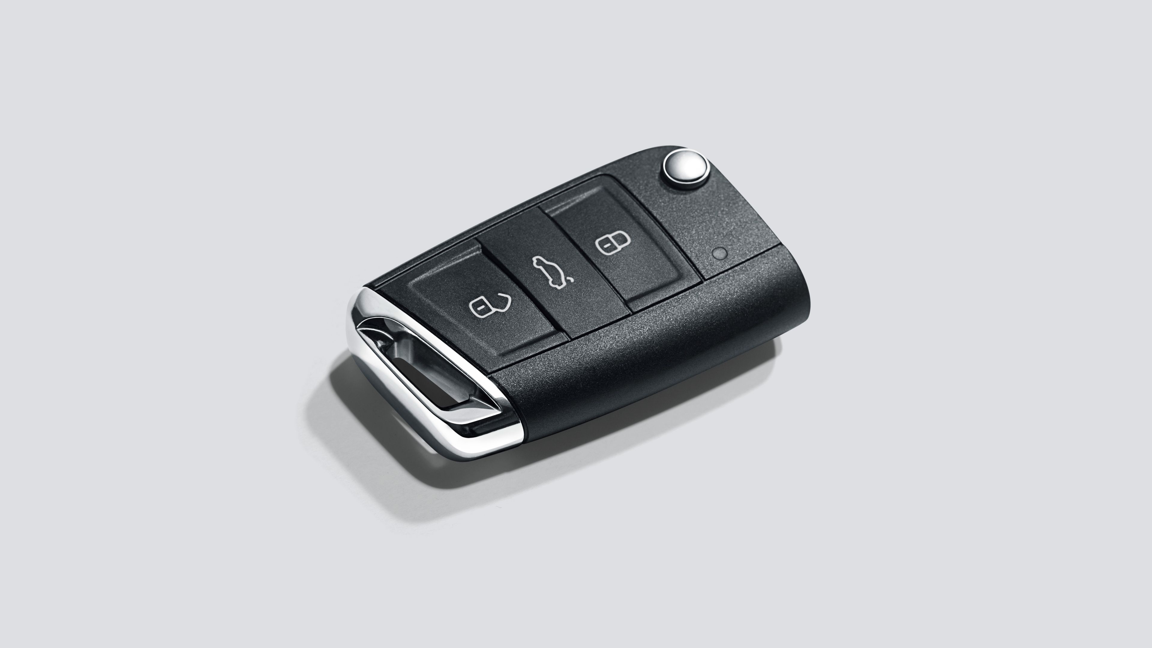 Čierny kľúč od automobilu s tromi tlačidlami na ovládanie vozidla. Tlačidlá na zamknutie a odomknutie dverí a otvorenie batožinového priestoru. Na strane kľúča je kovový úchyt.
