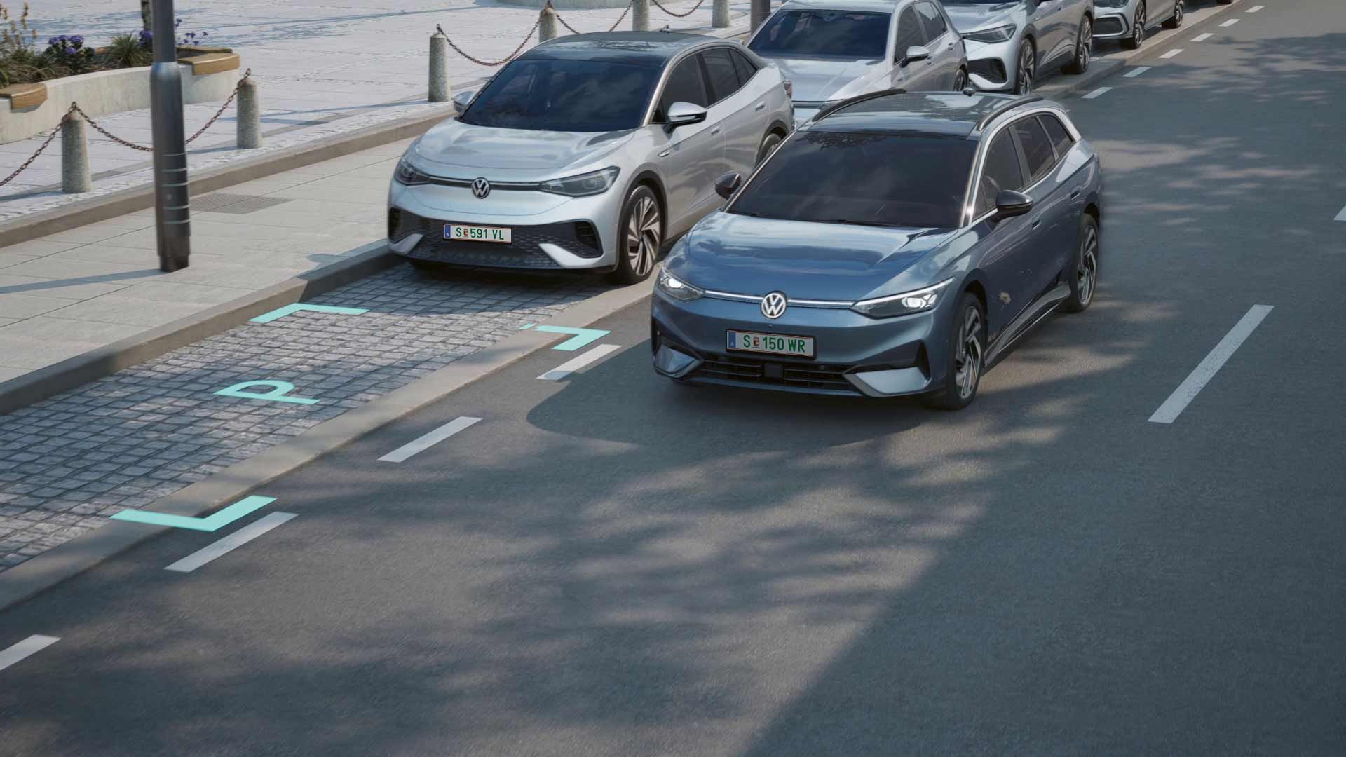 Dve vozidlá značky Volkswagen, jedno strieborné a jedno modré, jazdia autonómne a zaparkujú pred chodníkom. Na chodníku sú zábradlia a lavičky. Je slnečné popoludnie.