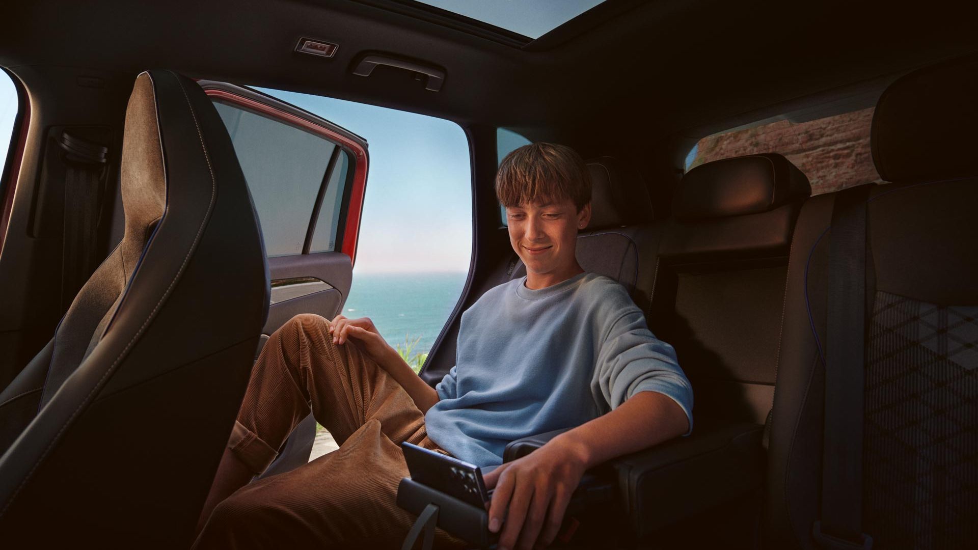 Interiér VW Tiguan, chlapec sedí na zadných sedadlách a používa tablet.