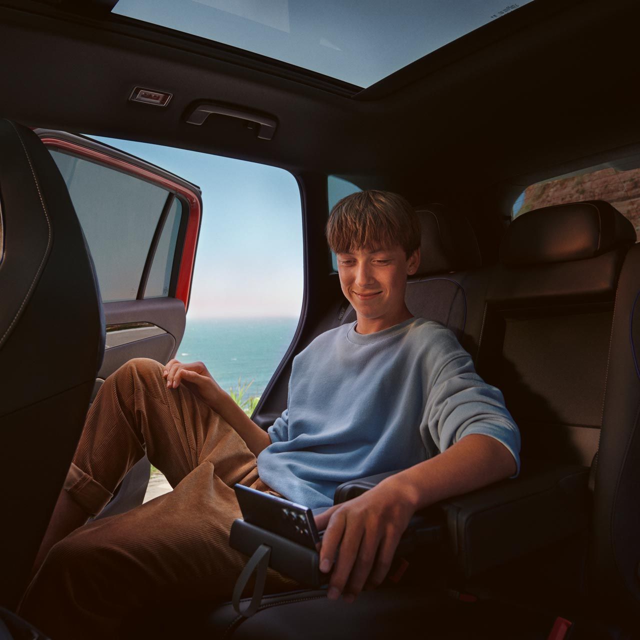 Interiér VW Tiguan, chlapec sedí na zadných sedadlách a používa tablet.