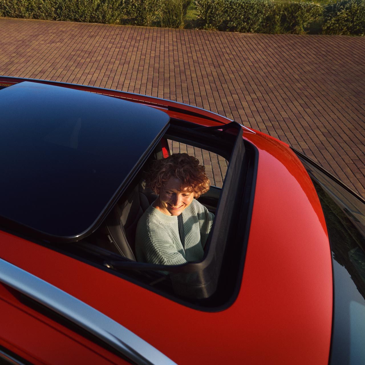 Čiastočne otvorená panoramatická výklopná a posuvná strecha. VW Tiguan. Na mieste vodiča vidieť sedieť mladú ženu.