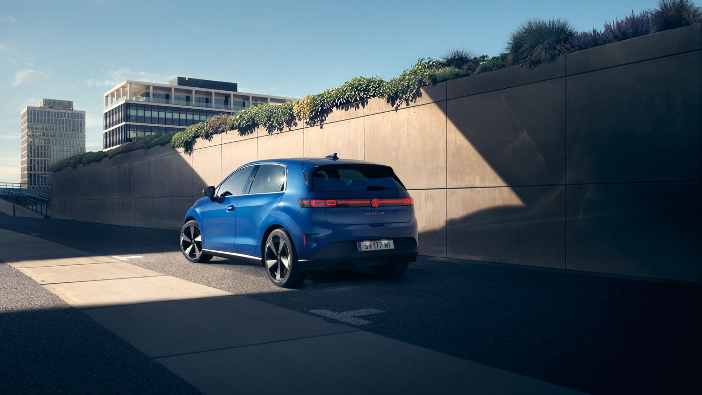 Modrý VW ID. Polo Style stojí na kraji cesty pri betónovej stene.