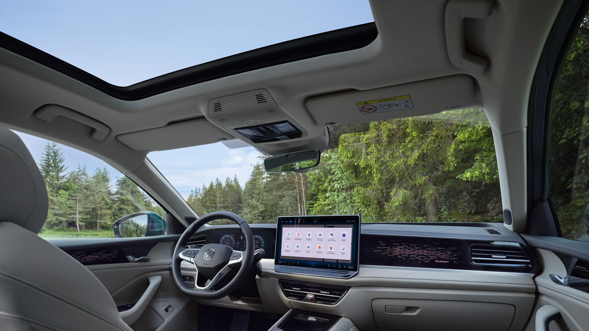 Pohľad do interiéru VW Passat s výhľadom na voliteľné sedadlá ergoActive, volant, digitálny prístrojový panel, palubnú dosku, displej systému infotainment a stredovú konzolu. Elegantný charakter mu dodáva ambientné osvetlenie. Cez čelné sklo je výhľad na les.