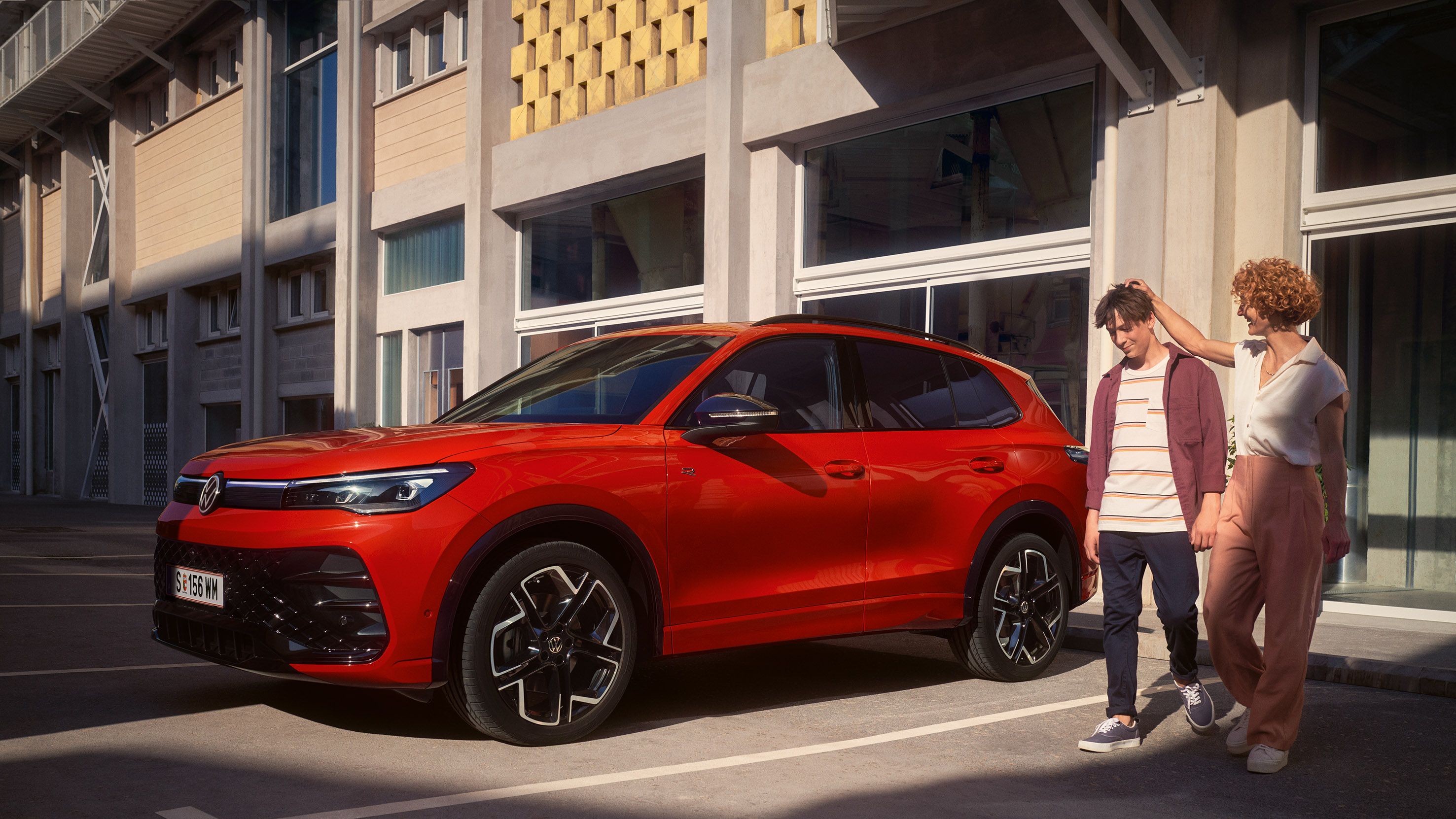 Červený VW Tiguan zaparkovaný pred budovou.