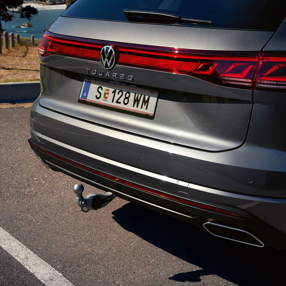 Pohľad na voliteľné ťažné zariadenie VW Touareg Elegance. Vozidlo stojí na ceste, v pozadí vidieť stromy a pobrežie.