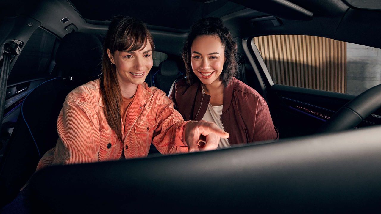 Dve ženy používajú systém infotainment vo vozidle značky VW.