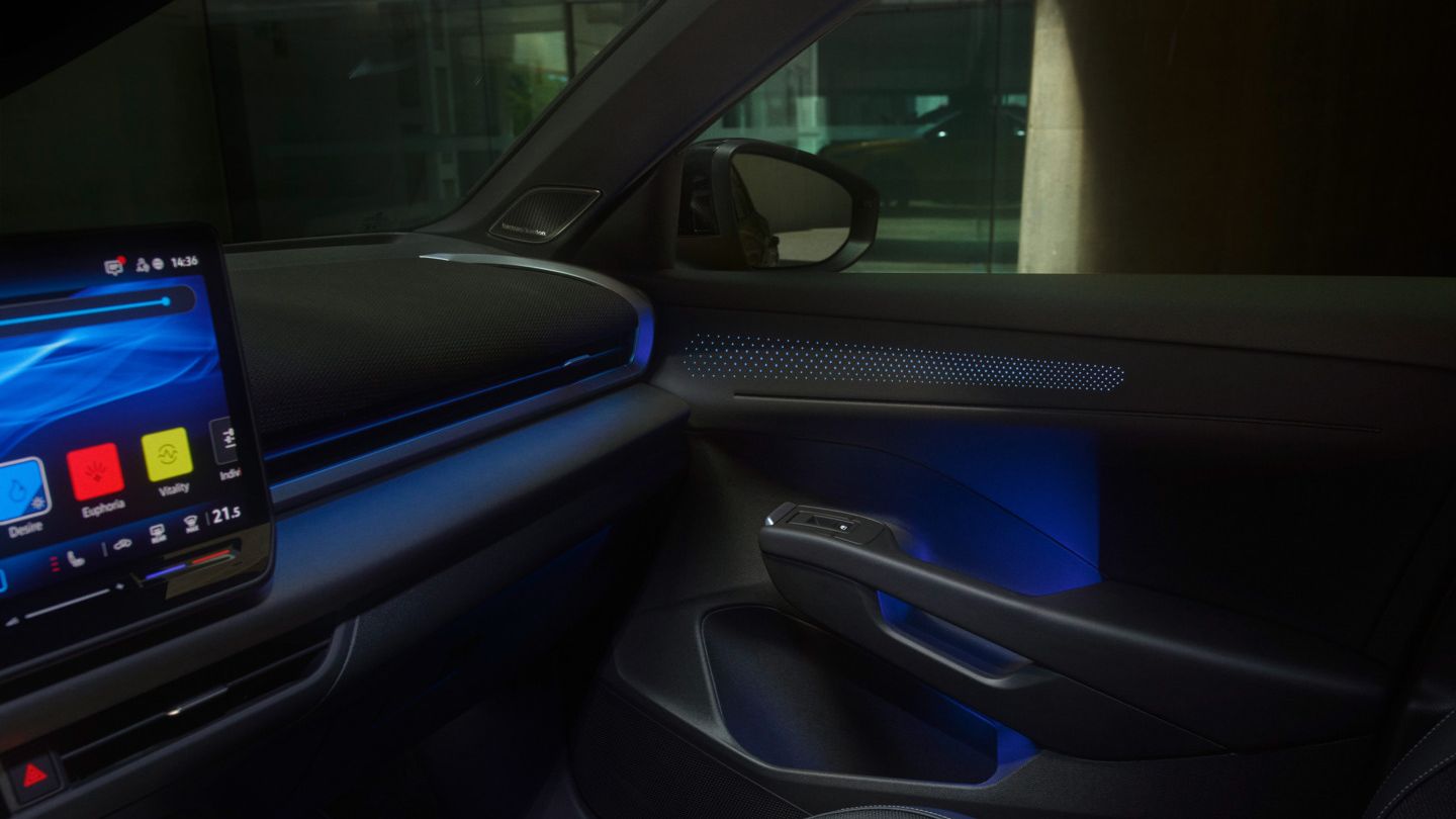 Interiér modelu T-Roc s osvetleným dotykovým  systémom infotainment, ktorý zobrazuje navigačné funkcie, hudbu a informácie o počasí. Osvetlenie interiéru je modré a vytvára futuristickú atmosféru. Dizajn je štíhly a minimalistický.