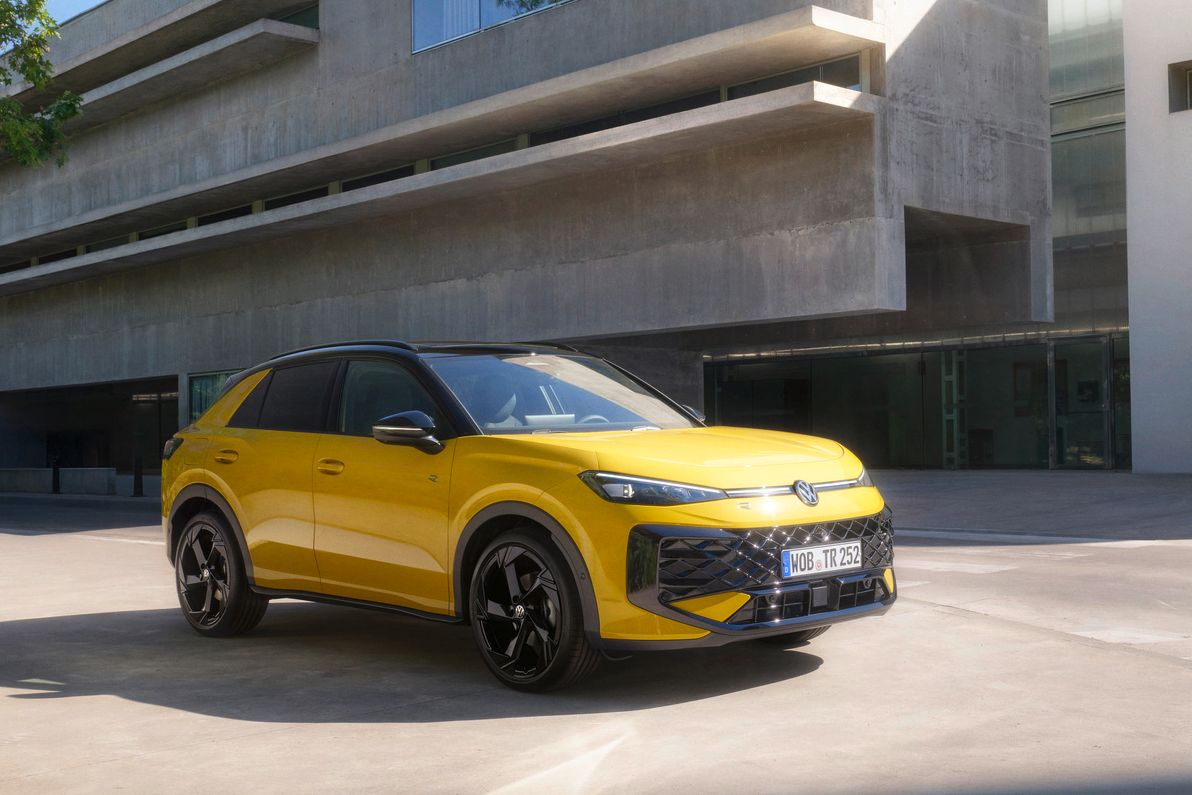 Volkswagen T-Roc zaparkovaný pred exkluzívnou betónovou budovou. Vedľa budovy je krásny vysoký strom a zeleň.