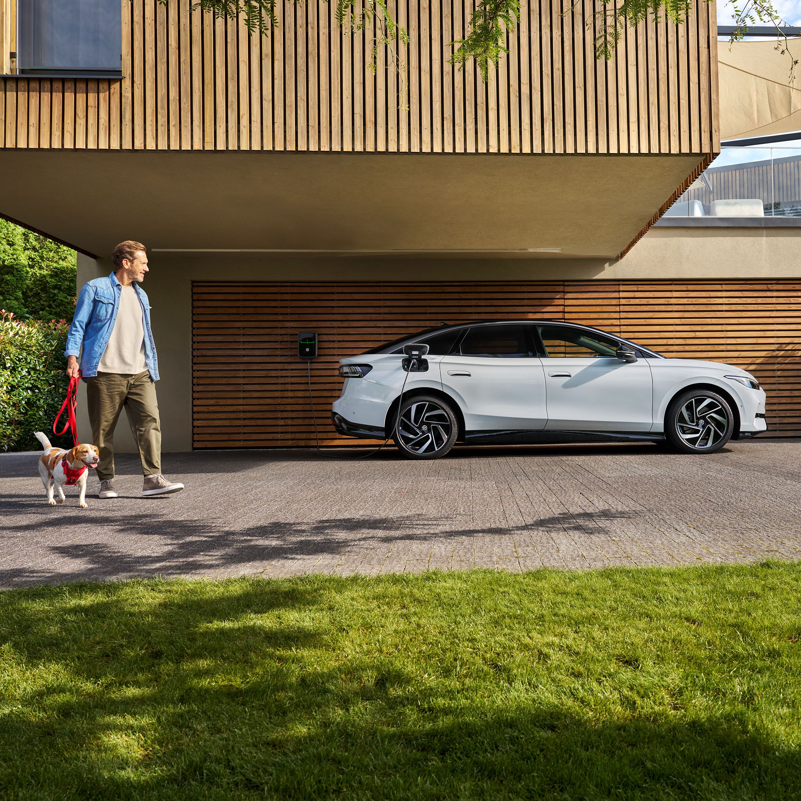 Muž so psom vedľa VW ID. Nabíjacia nástenná nabíjačka.