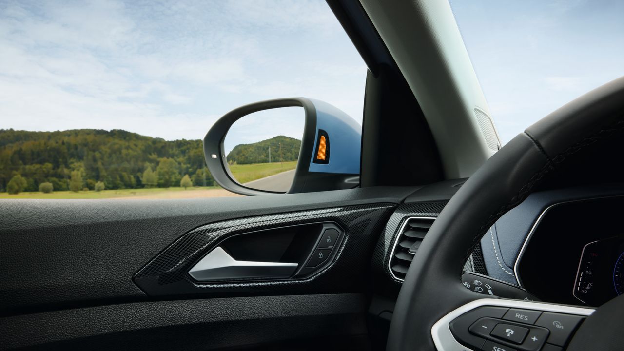Detailný záber na spätné zrkadlo vodiča modrého VW T-Cross.