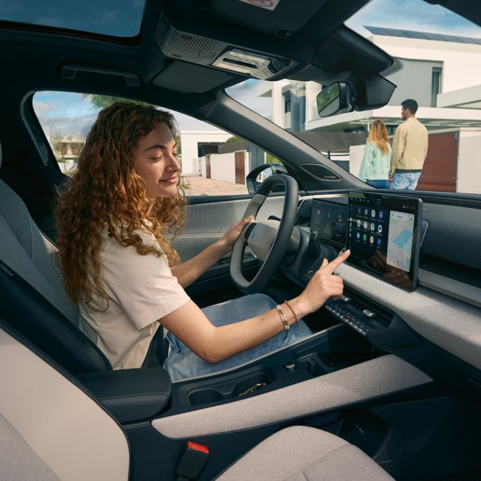 Mladá žena sedí za volantom VW ID Cross a ovláda infotainment systém.
