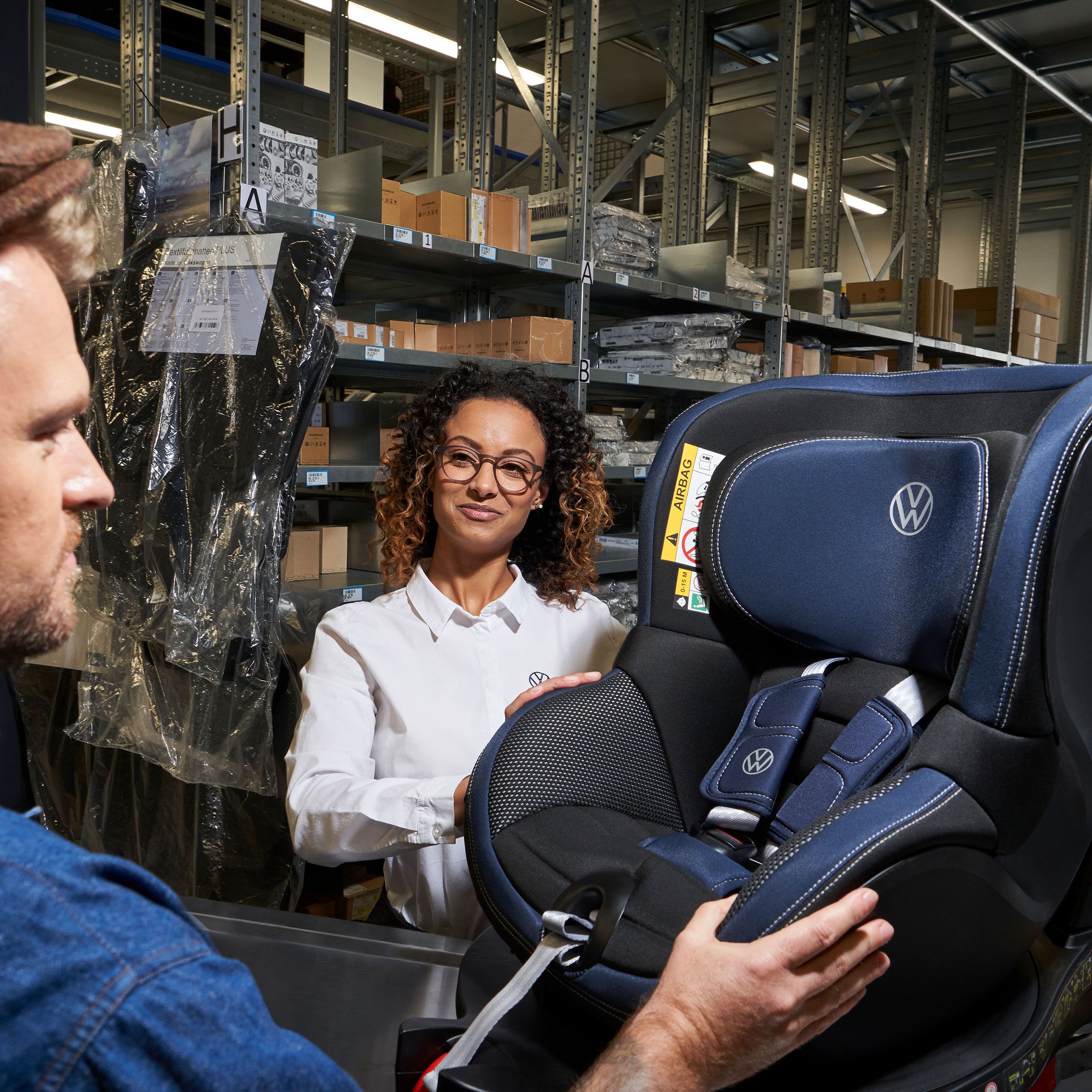 Zamestnanec servisu VW a zákazník si prezerajú detskú autosedačku VW