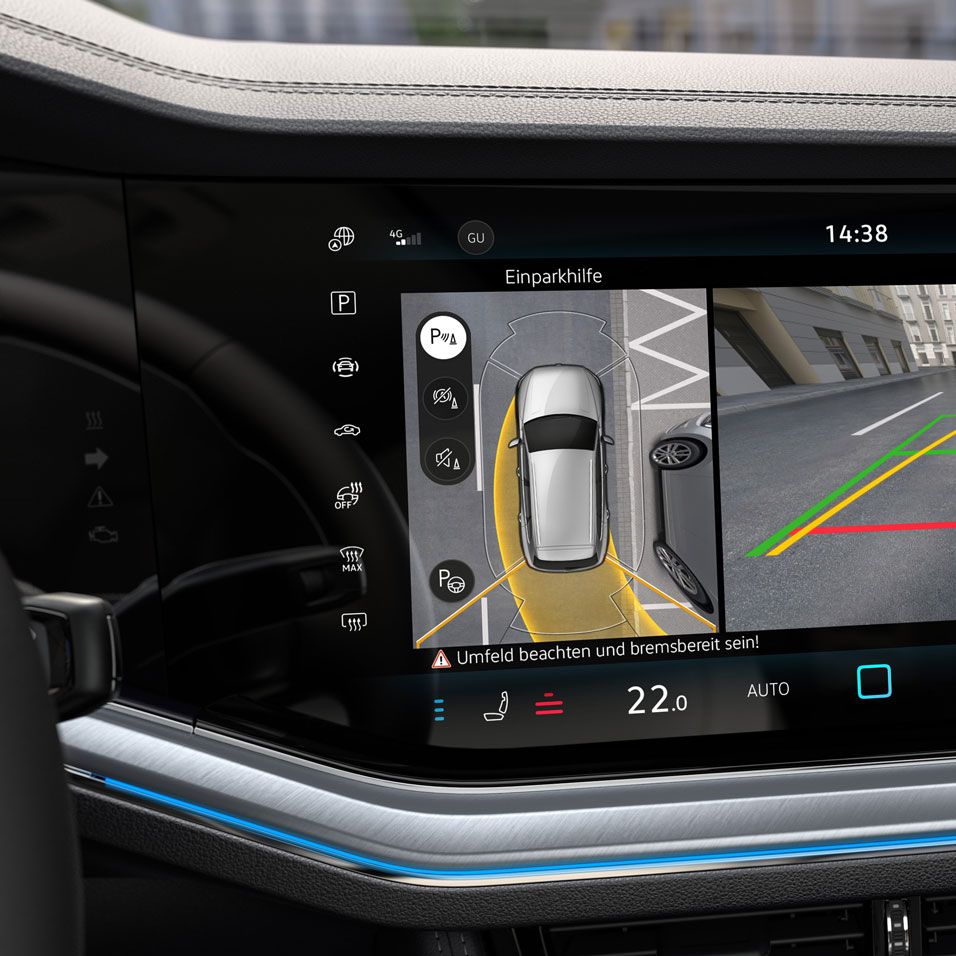 Dotykový displej systému infotainment zobrazujúci obraz z cúvacej kamery. Na ľavej strane je zobrazený pohľad zhora na zaparkované auto. Na pravej strane sú farebné línie, ktoré pomáhajú vodičovi pri parkovaní.