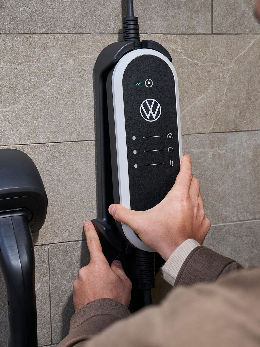 Muž pripevňuje nástenný držiak na nabíjaciu sadu ID. Charger Travel Basic na stenu