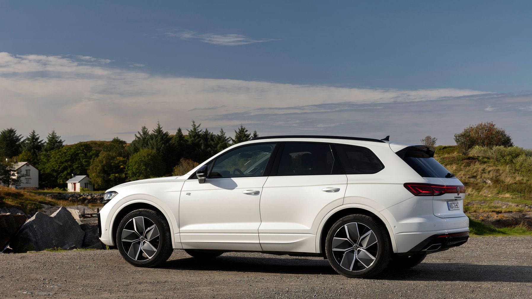 Volkswagen Touareg zaparkovaný na štrkovom povrchu pri jazere.