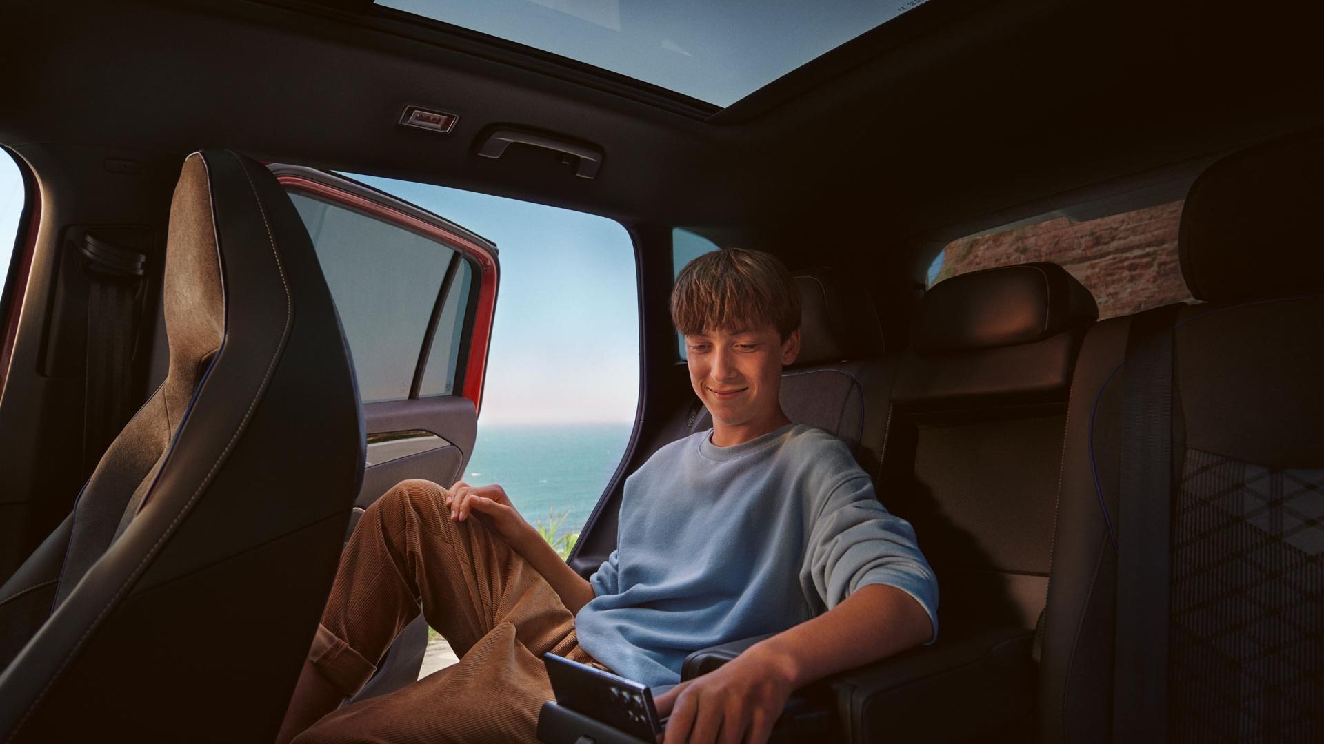 Interiér VW Tiguan, chlapec sedí na zadných sedadlách a používa tablet.