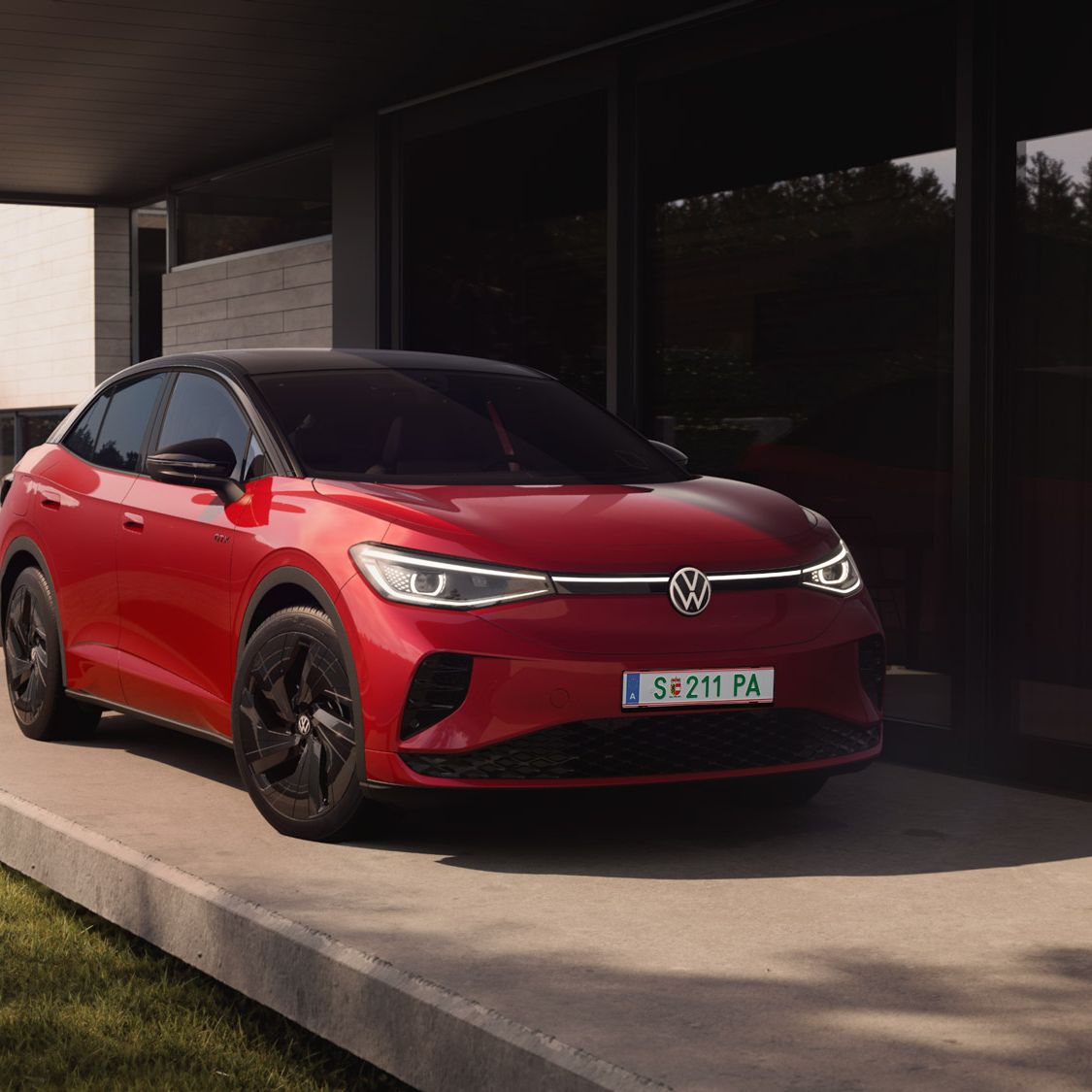 Červené elektrické SUV Volkswagen ID.5 GTX zaparkované pred moderným domom. Naokolo je pekne upravená zeleň.