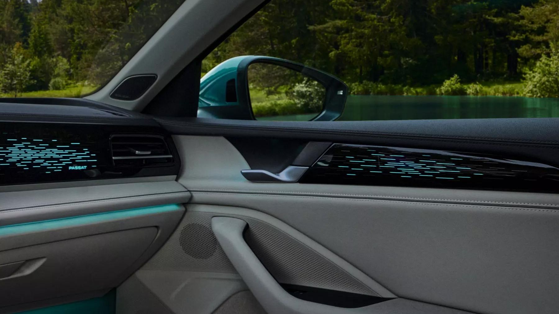 Interiér auta s moderným dizajnom. Viditeľné je dizajnové ambientné osvetlenie na dverách a palubnej doske. V pozadí je zelený les.