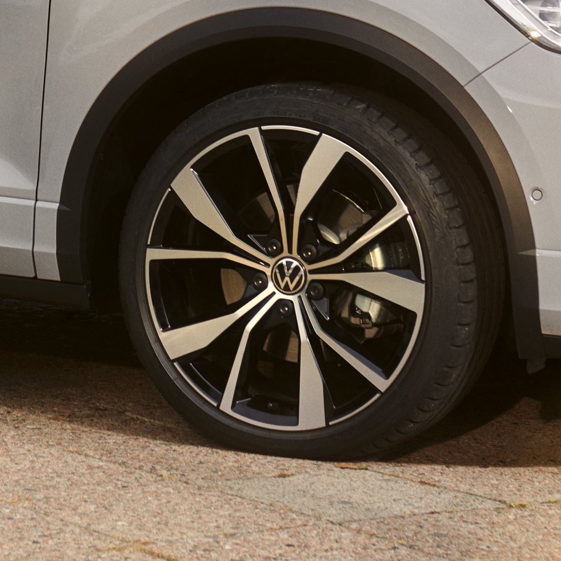 VW T-Roc v bielej farbe, detail na disk Misano v čiernom/leštenom vyhotovení. Čiastočne vidieť predný nárazník a dvere. 
