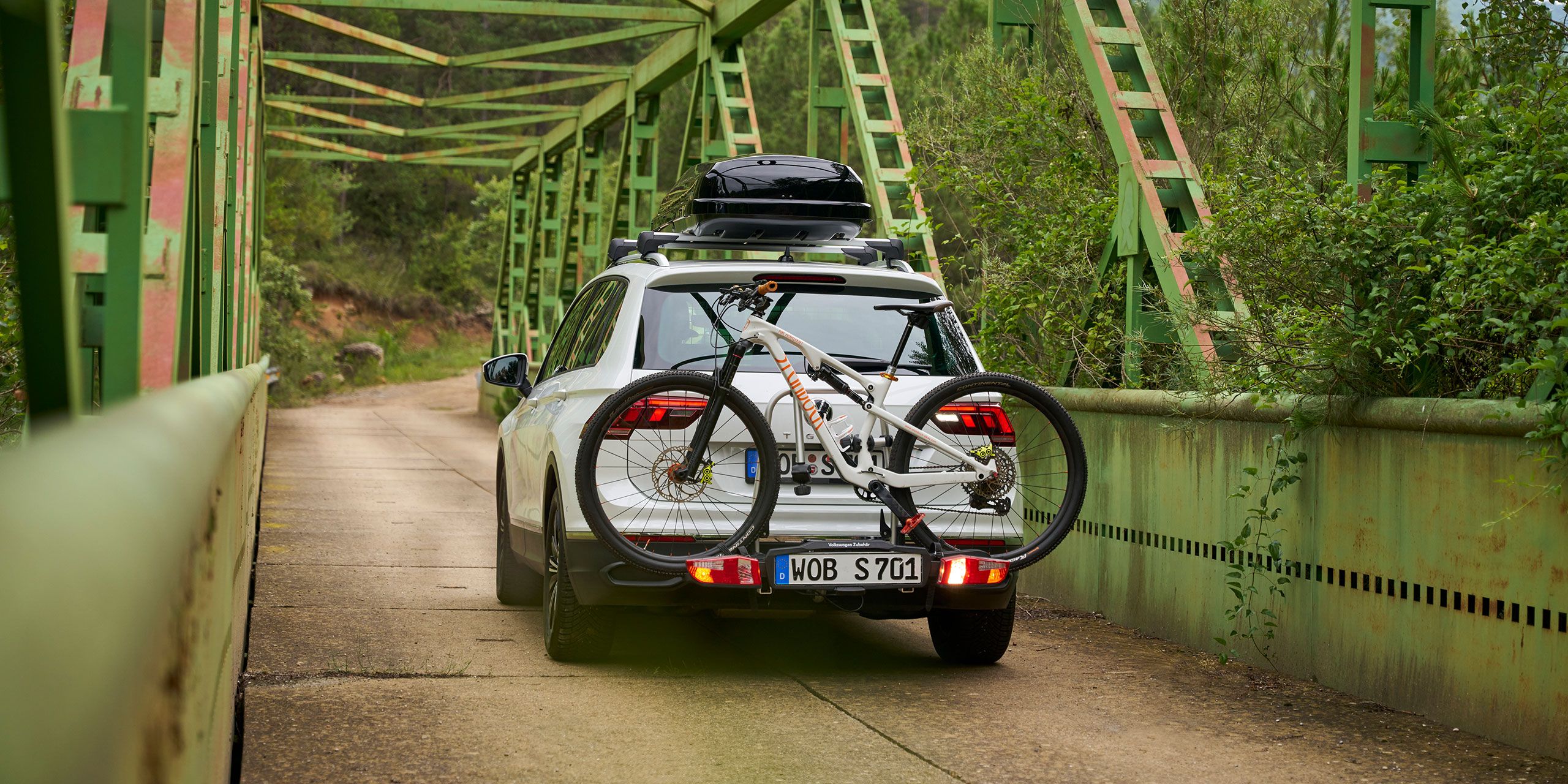 VW Tiguan s strešným boxom a nosičom bicyklov VW príslušenstva  vrátane prejazdov bicyklov cez most