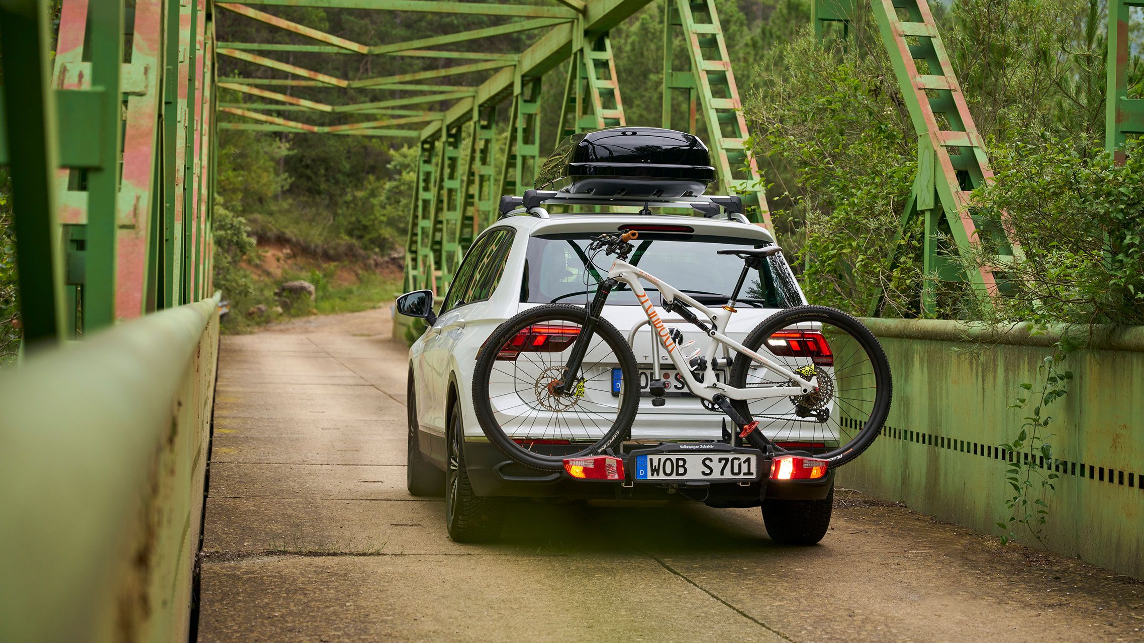 VW Tiguan s strešným boxom a nosičom bicyklov VW príslušenstva  vrátane prejazdov bicyklov cez most
