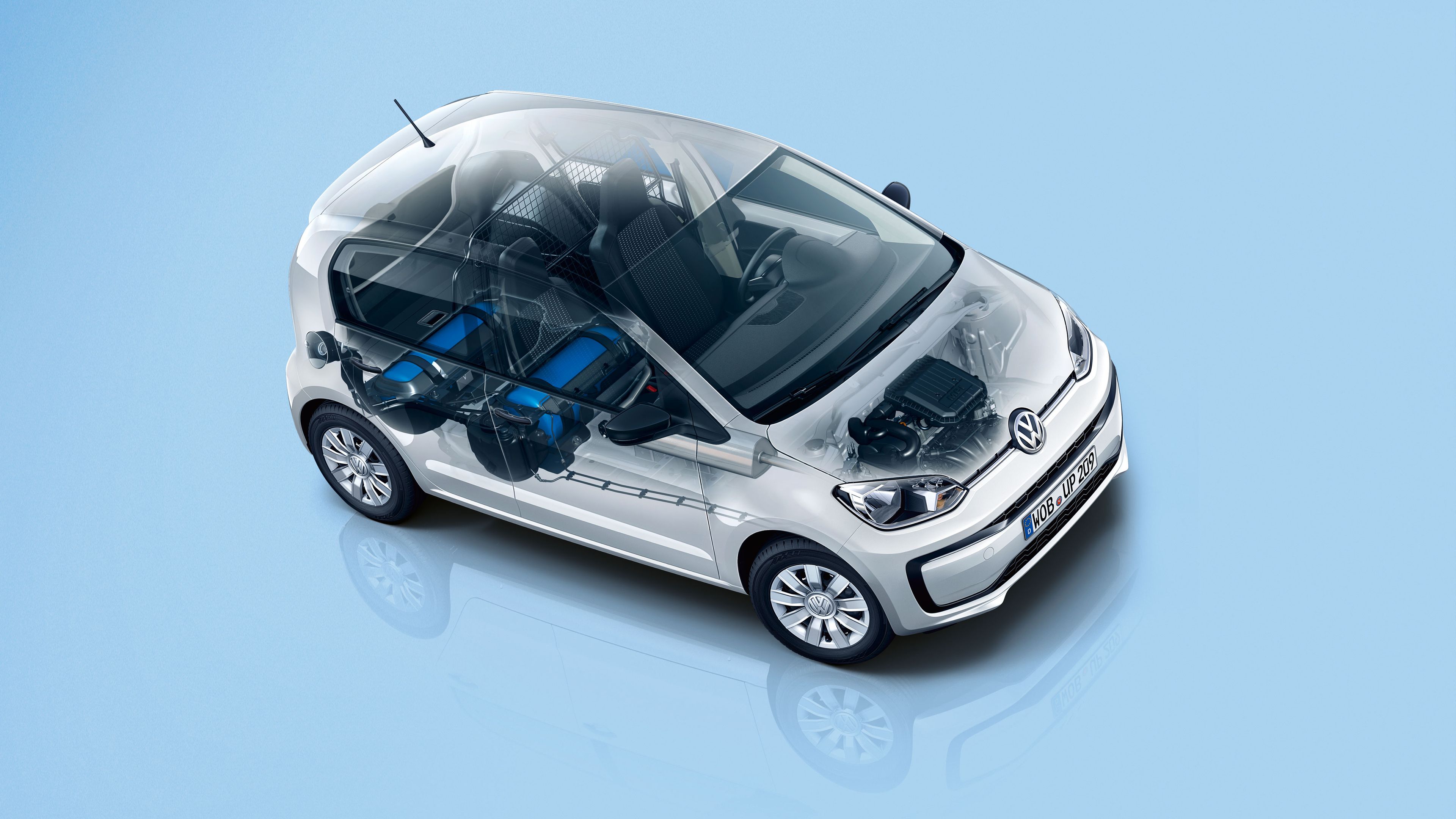 Priehľadný obrázok automobilu Volkswagen ukazuje vnútorné komponenty ako nádrže na plyn, motor a káblové vedenie. Auto je malé, biele a stojí na modrom pozadí. Má moderný dizajn a kompaktnú konštrukciu.