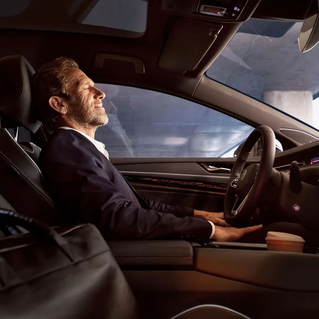 Muž sedí vo svojom vozidle Volkswagen, má zatvorené oči a používa aplikáciu Wellness.