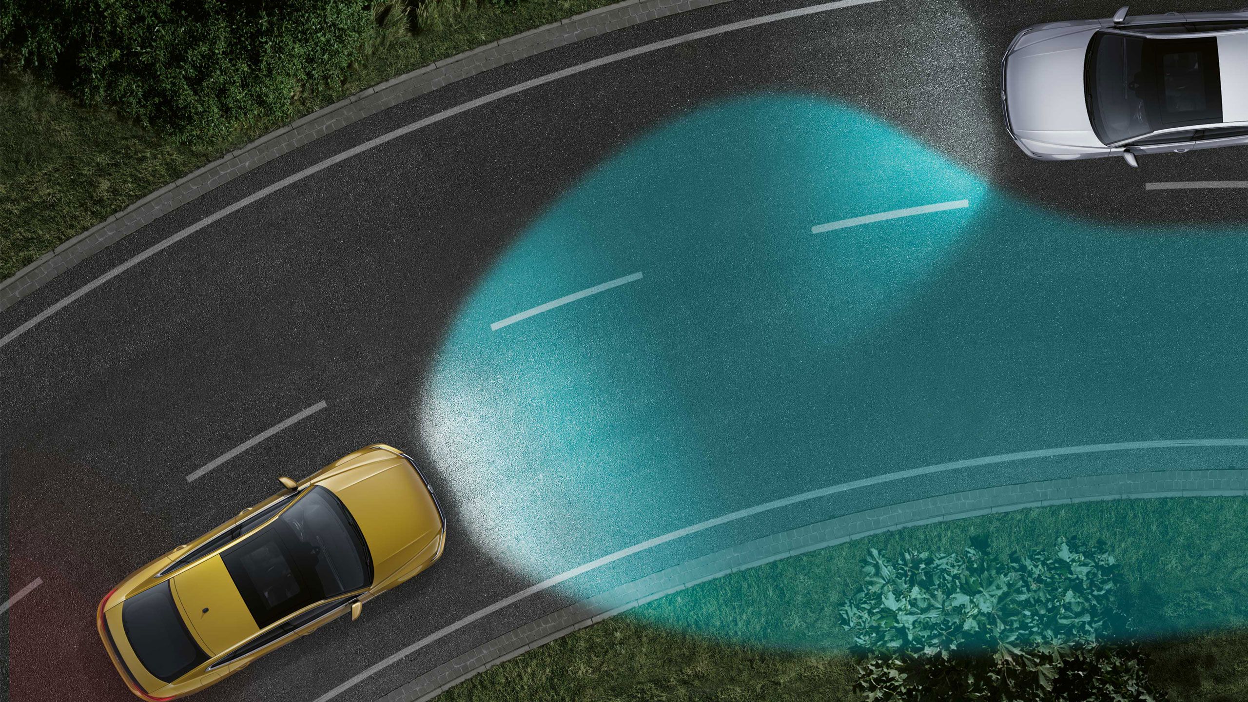 Auto s adaptívnymi svetlami jazdí po nočnej ceste, kde osvetľuje zákrutu a neoslňuje protiidúce vozidlo. Protiidúce vozidlo sa nachádza na vrchole zákruty. Na ceste je prerušovaná stredová čiara.