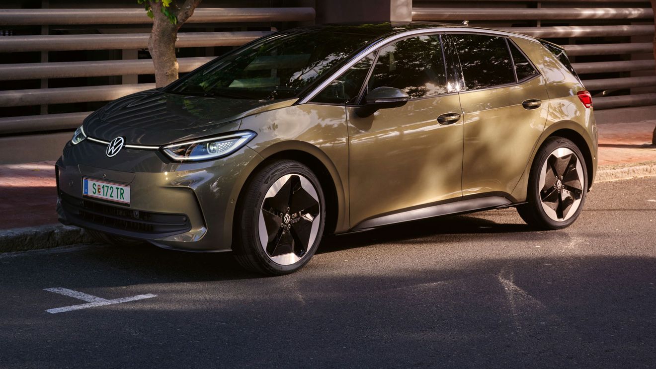 VW ID.3 v olivovo zelenej farbe je zaparkovaný v meste pri modernom bytovom dome.