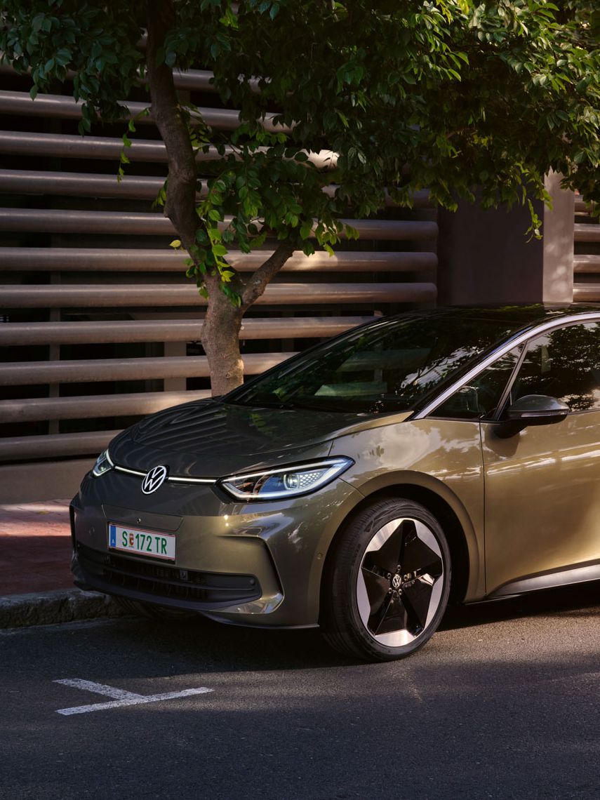 VW ID.3 v olivovo zelenej farbe je zaparkovaný v meste pri modernom bytovom dome.