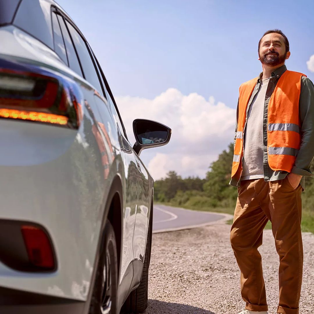 Muž v reflexnej veste stojí vedľa svojho VW ID. na okraji cesty.