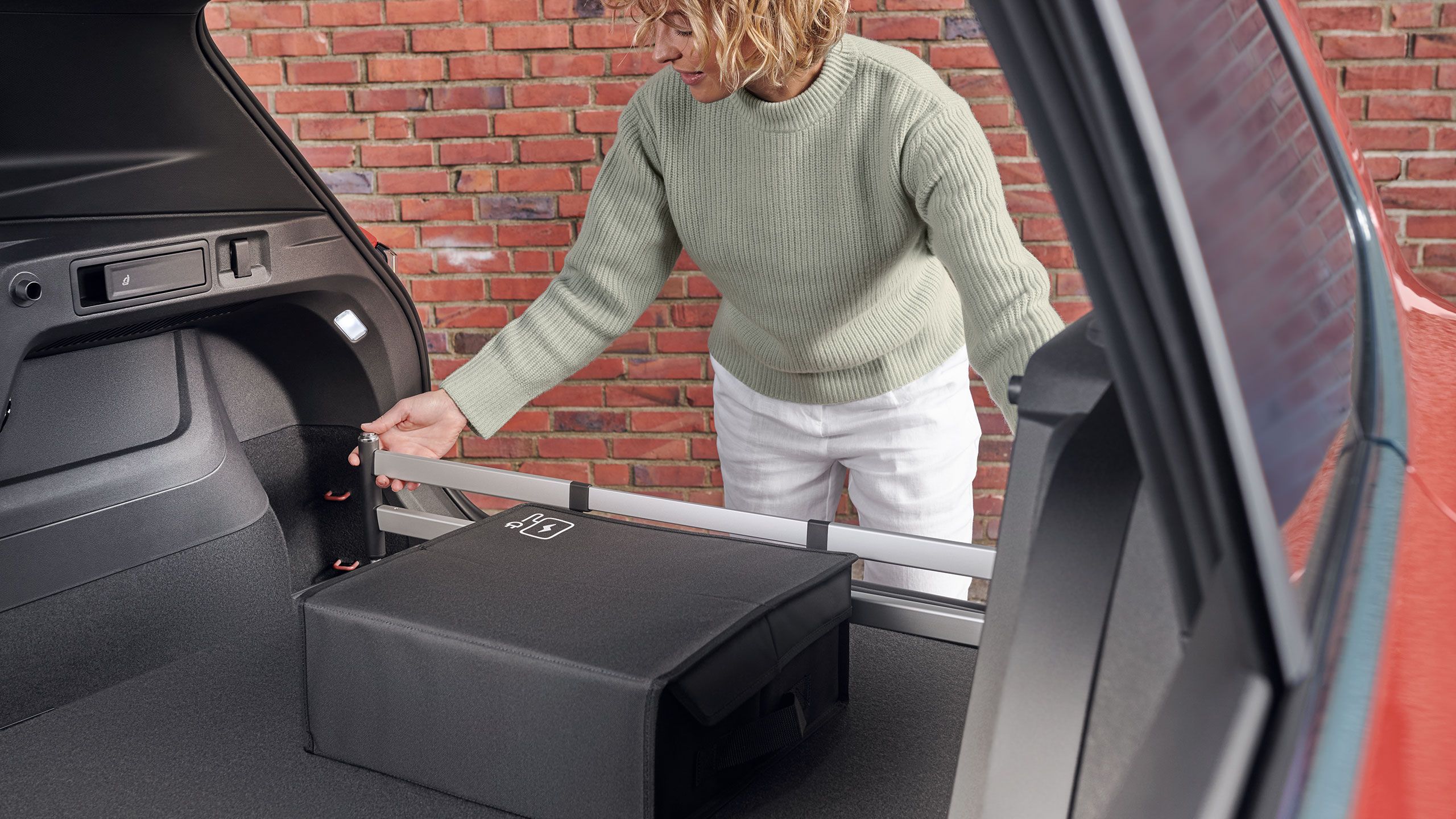 Žena montuje zásuvný modul do batožinového priestoru od VW do batožinového priestoru vozidla VW