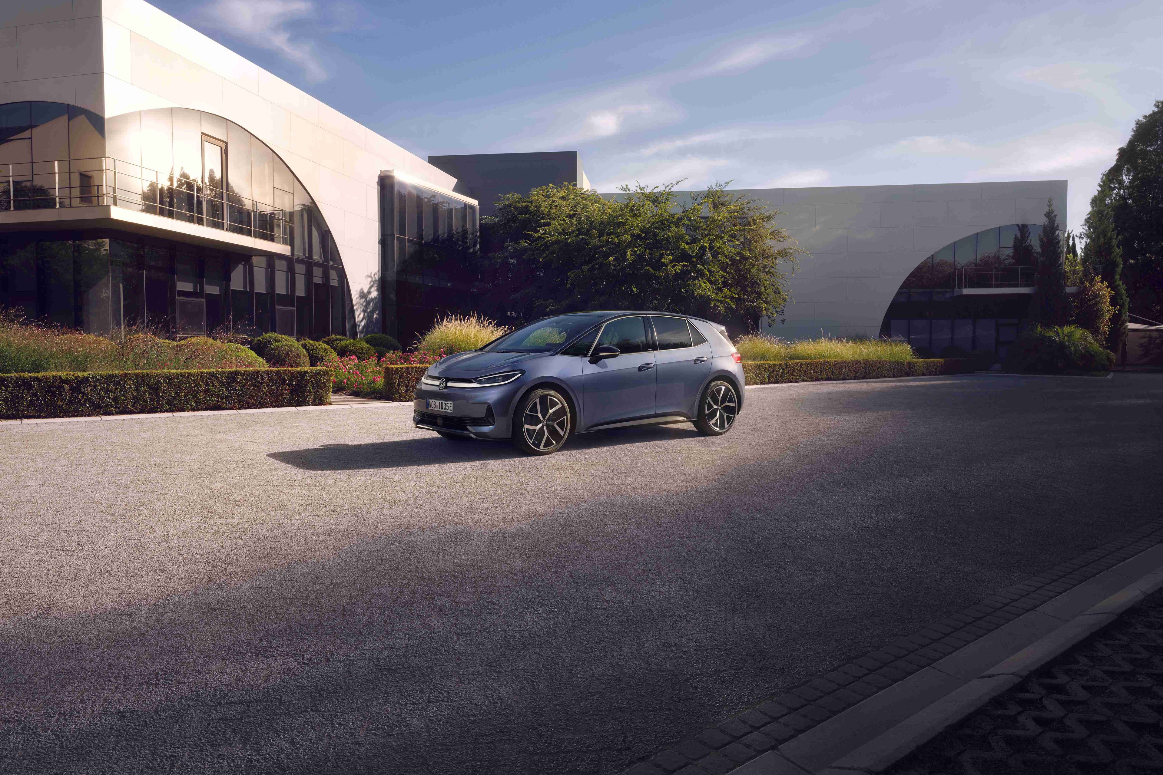 Volkswagen ID.3 Neo zaparkovaný na parkovisku pred modernou verejnou budovou, ktorú osvetľuje slnko.