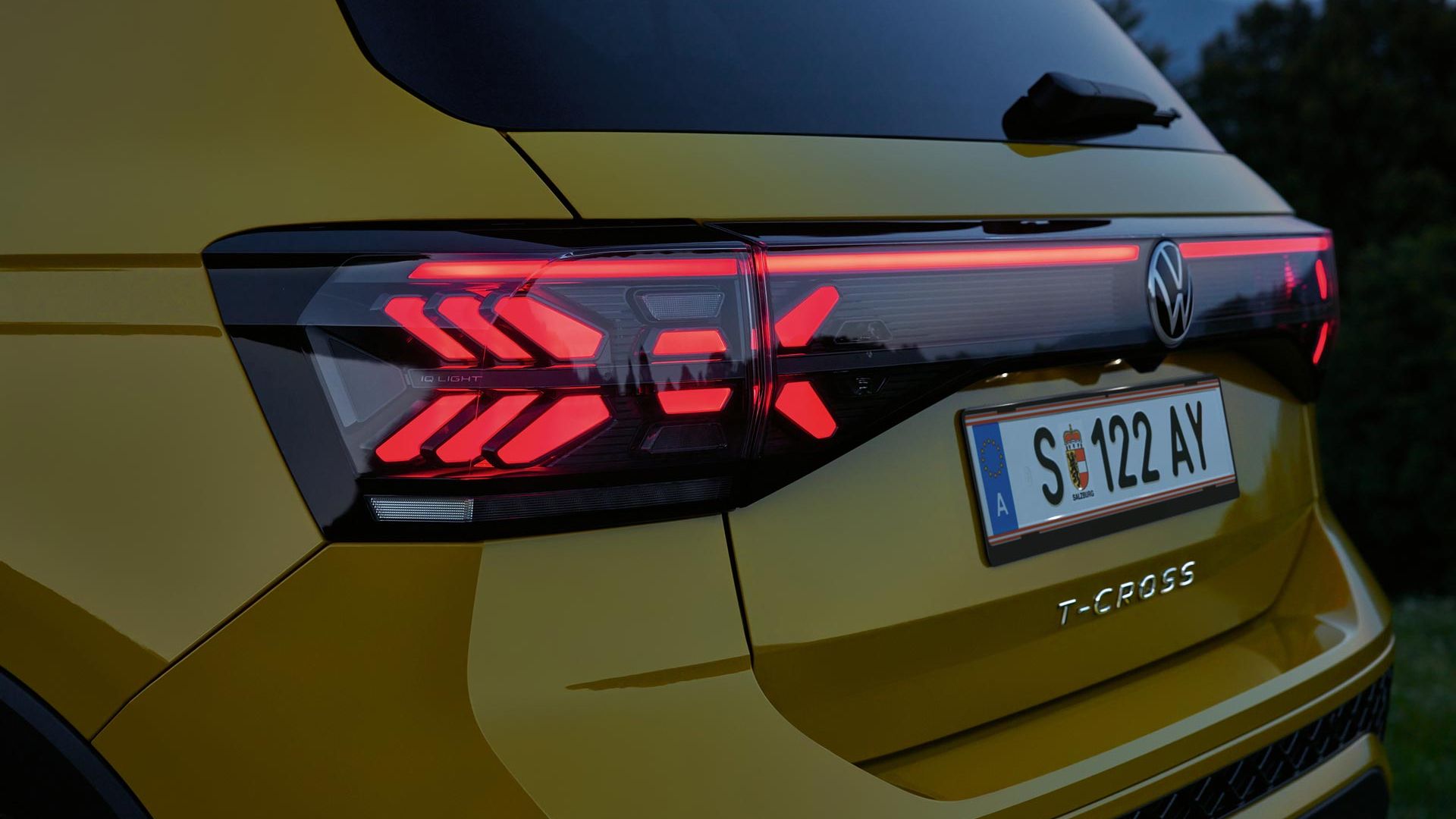Detail na zadné svetlá žltého VW T-Cross za súmraku.