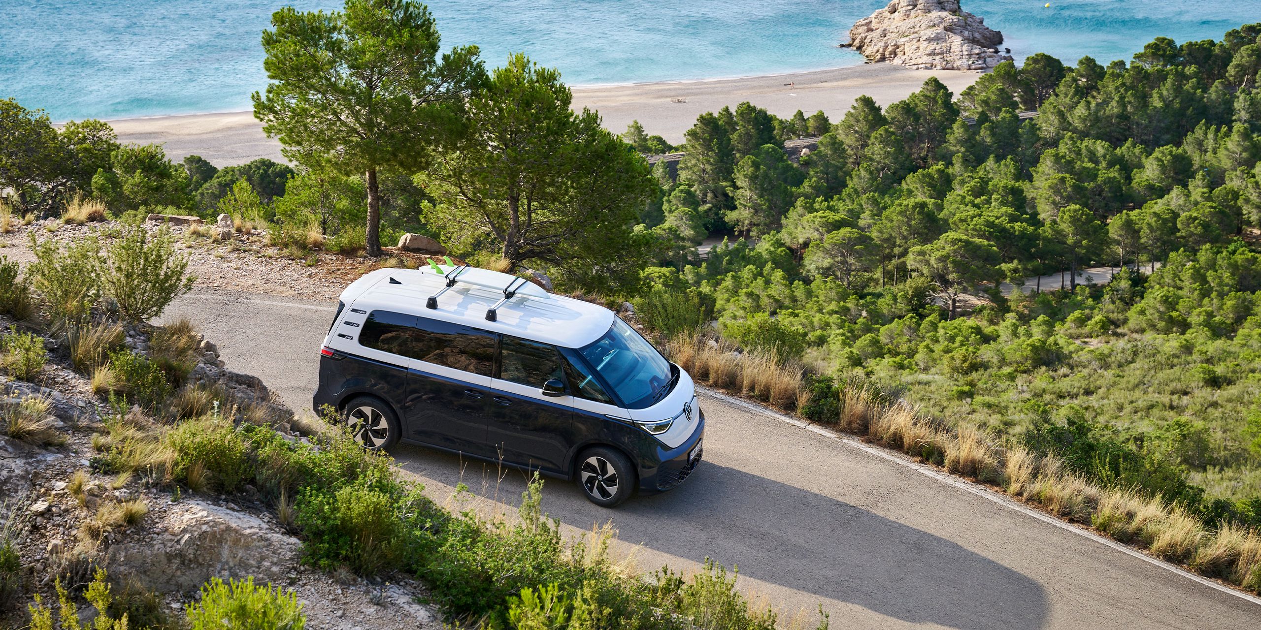 VW ID. Buzz so surfom na streche prechádza zákrutou