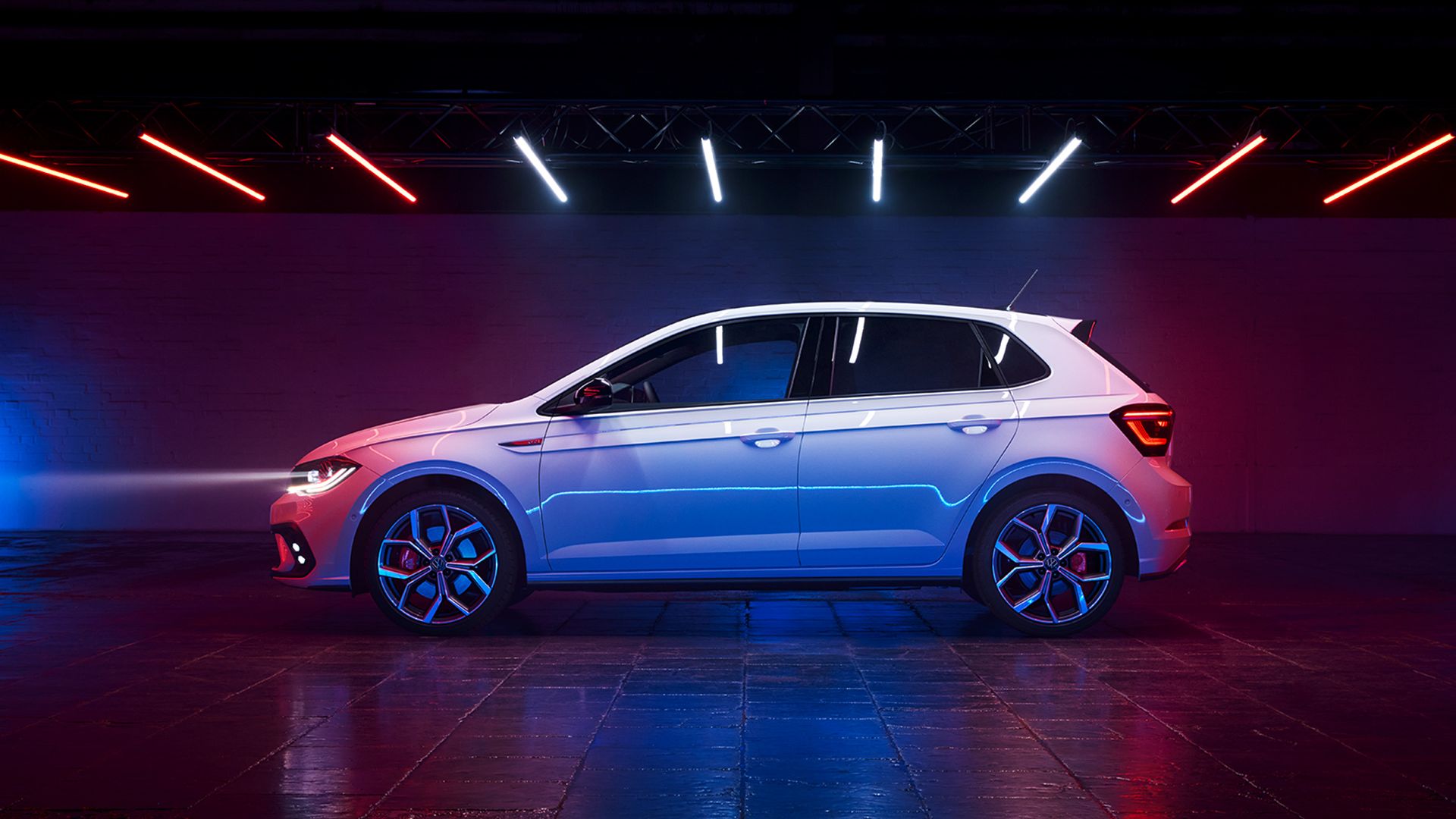 Pohľad na bok bieleho VW Polo GTI s tónovanými zadnými oknami, logom GTI na blatníku a voliteľnými 18-palcovými diskami "Faro".